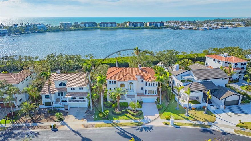Welcome to the secure, double-gated Bay Isles Bayou community on Longboat Key. Set on an exclusive waterfront lot just two houses down from the open waters, this extraordinary estate boasts over 5,700 square feet of refined living space, capturing breathtaking west-facing views over Buttonwood and Cranes Bayou. Step inside to soaring 20-foot ceilings, a magnificent crystal chandelier, and an inviting formal great room adorned with custom built-ins and a stately fireplace—each detail reflecting the grandeur and grace of this one-of-a-kind residence. This home features four expansive bedrooms, four full baths, and two half baths, along with an updated hydraulic elevator for seamless access to every level. The heart of the home is this chef’s kitchen that features quartz and granite countertops, exquisite European-style cabinetry, and top-of-the-line Wolf and commercial-grade appliances. A spacious center island with a prep sink provides ample workspace, while stunning water views elevate every culinary experience. The owner’s suite is a true private retreat, offering separate baths and an astonishing 300+ square foot walk-in closet. A private staircase leads to the primary office, where walls of windows frame sweeping bayfront panoramas—an inspiring space for work or quiet reflection. A modern spiral staircase with glass railings leads to the second level, where two additional en-suite bedrooms and a sprawling den await. Added in a 2011 renovation, the den features floor-to-ceiling bayfront windows, a private half bath, and access to the upper-level sunset terrace—the ultimate sanctuary to soak in the Gulf’s radiant hues. Designed for true indoor-outdoor living, the fully enclosed lanai features electric retractable screens, a spa-like pool with an elevated hot tub, and sweeping water views that are the perfect backdrop for sunset soirees.. Boating enthusiasts will delight in the oversized dock, equipped with a 10,000-lb boat lift and a 2,000-lb hoist for jet skis or other water toys, ensuring effortless access to Longboat Key’s world-class waterways. Beyond its breathtaking beauty, this home offers peace of mind and lasting quality, with recent upgrades including a newer roof, all-impact windows and doors throughout, a whole-house automatic generator, all-new AC units, a private well for irrigation, and new hot water heaters—ensuring effortless luxury for years to come. As a Bay Isles resident, you’ll enjoy exclusive access to the Bay Isles Beach Club, a private Gulf-front oasis. Nearby, the Longboat Key Club offers championship golf, award-winning tennis, a Gulfside pool deck, a state-of-the-art fitness center, spa services, and fine dining, along with a full-service marina for yachting enthusiasts. Stroll or bike to Publix, the public tennis center, town hall, the library, and local art shows at the Caron Family Pavilion. Just a short drive away, indulge in the luxury shopping and culinary delights of St. Armands Circle, the cultural energy of Downtown Sarasota, and the convenience of Sarasota International Airport. This grand waterfront residence offers an unrivaled price per square foot—a rare opportunity in this highly coveted enclave. While a discerning buyer may wish to personalize some cosmetic details, the most critical and costly updates have already been addressed, ensuring seamless, stress-free luxury living. Here, at the water’s edge, coastal dreams come to life. This is more than a home—it’s a lifestyle.
