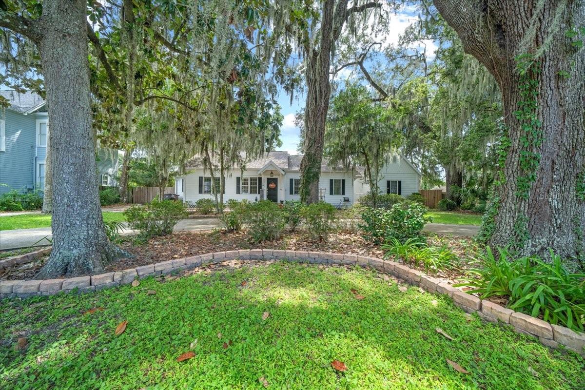 Welcome to this storybook home tucked away in the heart of the historic district, where timeless charm meets modern comfort. This beautifully maintained three-bedroom, two-bathroom residence with a two-car garage was built in 2006 and has been thoughtfully updated to offer peace of mind and style. The curb appeal is undeniable, with a graceful circular driveway, fresh exterior paint in 2024, and mature trees that are even home to a sweet owl family, adding to the property’s unique character. Step inside and you’ll find a warm, inviting interior where natural light filters through shutter blinds and highlights the spacious living areas. The home boasts a brand-new AC unit in 2023, newer appliances, new master vanity, and updated flooring in two rooms and the loft in 2023, ensuring modern convenience blends seamlessly with historic charm. Even the finer details, like new toilets in 2024, have been thoughtfully cared for. The large master suite offers a tranquil retreat, while the loft above the garage provides flexible space perfect for a home office, playroom, or creative studio.
Out back, enjoy mornings and evenings on the screened-in porch overlooking the peaceful yard—a wonderful extension of the home’s living space. Located in a golf cart-friendly community, this property is within walking distance to downtown’s vibrant shops, dining, and events, all while being zoned for some of the area’s most sought-after schools. With its 2021 roof, thoughtful updates, and irresistible charm, this home is truly a rare opportunity to enjoy modern living in a setting filled with history, character, and a touch of whimsy.