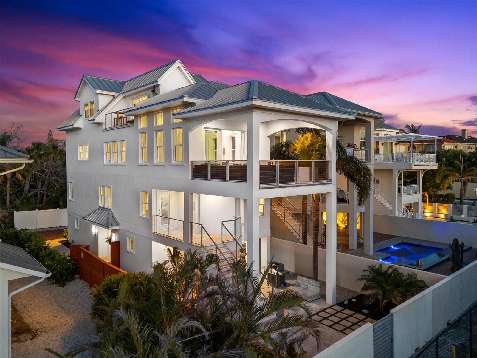 Modern Luxury, Minimal Upkeep—The Perfect Siesta Key Escape. Luxury meets practicality in this stunning, low-maintenance Siesta Key home on the quiet and desirable North End. Designed for modern lifestyles, this contemporary retreat offers breathtaking Gulf views, exclusive deeded beach access, and a flexible multi-level layout—perfect for entertaining or relaxing. Built with sustainable, storm-resistant materials, this home provides peace of mind, energy savings, zero-yard work, and is near Siesta Village, the North bridge, and downtown Sarasota, so you can focus on living. *Effortless Living with Mesmerizing Views* The 3rd floor main living area is designed for effortless entertaining and relaxation. A gourmet chef’s kitchen, complete with high-end appliances, custom cabinetry, and quartz countertops anchors the space, flowing seamlessly into an open-concept dining and living area. Step onto the expansive lanai to soak in panoramic glimpses of the Gulf, Big Pass, and Lido Key—the perfect spot for your morning coffee or sunset cocktails. *Flexible Spaces for Comfort & Privacy* Thoughtfully designed for privacy and togetherness, this home features a unique multi-level layout that ensures everyone has their own space while staying connected. The primary suite occupies the entire 4th floor, creating a private sanctuary complete with a spa-inspired bath, dedicated workspace that can easily be converted into a walk-in wardrobe, and an open balcony with coastal breezes and shimmering water views. On the 2nd level, three bedrooms and two full baths provide a comfortable retreat for family and visitors. A secondary living area with patio on this floor offers a versatile space—perfect for a media room, play area, or private lounge, plus easy access to the garden and beach access via exterior stairs. With the main living area positioned in between bedroom floors, there is just the right balance of separation and connection, ideal for multi-generational living, guests, or simply enjoying a sense of personal retreat within the home. *Architectural Excellence & Sustainable Design* Crafted with eco-conscious materials and smart design, this home is incredibly energy-efficient, providing long-term cost savings and environmental benefits. Built in 2017 by luxury homebuilder MGB – My Green Building, it feels like new and has been meticulously maintained. Designed to withstand Florida’s toughest storms, it has proven its fortress-like strength in recent weather events, delivering durability and peace of mind.
*A Versatile Retreat for Every Lifestyle* Designed for luxury and convenience, this home features a private elevator servicing all four floors, a flexible, open-concept layout, and ample space for both intimate gatherings and grand entertaining. Whether you envision it as a full-time home, seasonal escape, or a high-end investment property, it offers the ultimate Siesta Key lifestyle without HOA fees. Exclusive deeded beach access is just steps away. You can start your mornings with a peaceful stroll along the shore, launch a kayak or paddleboard into the turquoise water, or simply sink your toes into the soft, white sand. As the day winds down, sip a cocktail from your balcony while watching the legendary Siesta Key sunsets. As an added bonus, there is plenty of storage space for all your gear. This is more than just a home—it’s a private coastal sanctuary where every day feels like a vacation. Move in and start living your island dream today!