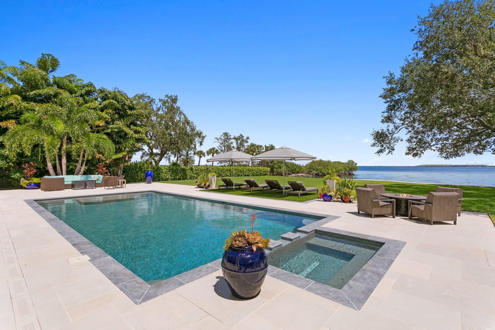 Introducing the perfect private coastal escape in the historic and scenic Ballast Point neighborhood of South Tampa. Be transported via a private road to a tranquil bayfront location surrounded by majestic oaks and inviting Old Florida charm. This estate property spans a FULL ACRE on the open bay and with a rarely found 150 ft. of water frontage. An award-winning coastal design, built by Sample Properties in 2018, welcomes you to refined finishes, dramatic designer appointments and superior outdoor living areas, with 5 bedrooms, 6.5 baths and over 5,000 square feet. Boasting magnificent views from almost every room, you are greeted by a double door entry to light-filled living spaces, great room with fireplace, dining room, warm hardwood floors and designer lighting, along with pecky cypress beam and wood accent ceilings. Sure to please the most discerning chef of the family, the custom kitchen delivers seamless design, center island and quartzite counters, custom cabinetry, integrated appliances (Sub-Zero/Wolf), 6-burner gas range and expansive walk-in pantry overlooking an informal dining/sitting area and water views beyond. Additional first floor living spaces include a mud room, powder bath and office. Upstairs, an impressive primary bedroom offers a private terrace, walk-in closet and spacious marble bath with dual vanities, dual water closets and soaking tub. Three additional ensuite bedrooms and laundry room complete the second living level. An intermediate level features a separate private guest/in-law suite offering a generous sitting area, bedroom, stunning bath and walk-in closet. The very best of this marvelous setting awaits outdoors with wide open water views, expansive covered terrace (blue marble), outdoor fireplace, dining area, outdoor kitchen, and pool bath. A heated pool/spa with custom cut limestone pool deck, plus waterfront Ipe deck complete the magazine worthy grounds. Exceptional exterior designed by Levell Design that includes custom railing, landscaping, pool deck, with no expense spared in the extraordinary marine-grade copper Aurora exterior landscape lighting system. Additional appointments include reinforced and recapped seawall 2020, separate cottage with storage and elevated living space (playroom, studio or home gym), along with an expanded 3-car garage. Convenient and walkable to the renowned Tampa Yacht Club, Bayshore Boulevard, Ballast Point park, this superior South Tampa estate delivers the ultimate in Florida Waterfront Living yet proximity to all that the City of Tampa has to offer.