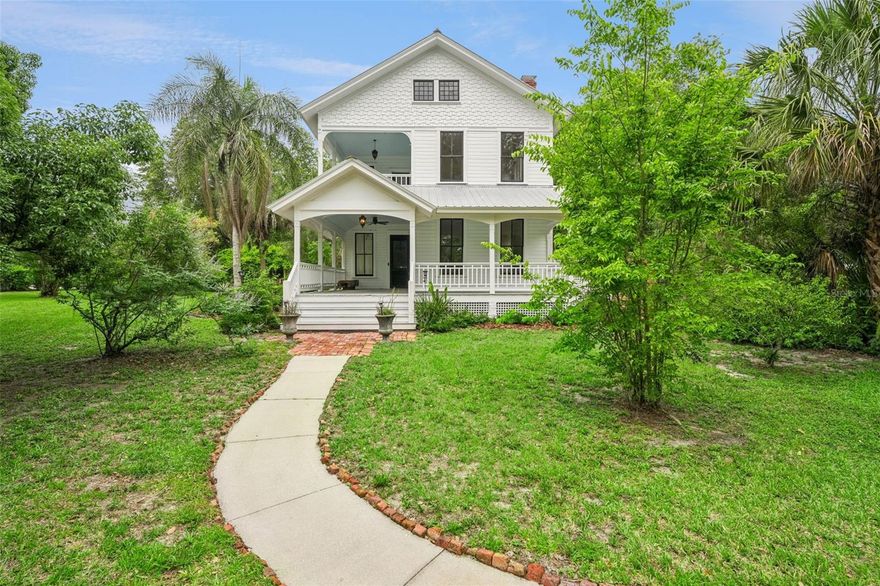 One or more photo(s) has been virtually staged. This luminous 1887 Victorian is a rare opportunity in Lake Helen’s historic corridor—restored with care, modernized for comfort, and wrapped in sunlight, character, and established gardens.

Inside, natural light pours through large east- and south-facing windows, accentuating tall ceilings and original architectural craftsmanship. Heart-of-pine floors flow across the first and second levels, complemented by pocket doors that transition from the dining room into a flexible living space—ideal as a music room, den, bedroom, or office. The front living area centers around a working fireplace, setting the tone for evenings of quiet comfort.  Photos have been digitally altered to remove all personal property on site. Best efforts have been made to preserve the characteristics of the property, though some minor changes may be present as a result of digital alterations.

The kitchen delivers volume and drama with vaulted ceilings, exposed oak beams milled in Lake Helen, abundant cabinetry, and a door that opens to a breezy side porch. A bright rear mudroom/laundry anchors the everyday entrance from the garage, and both levels offer full bathrooms for convenience. Bedrooms are generously sized—notable for a home of this vintage—and the upstairs suite opens to its own private balcony.

A fully finished third floor expands the home’s usable square footage with heat, air, four windows of daylight, and a lofty vantage point where you can watch launches from Cape Canaveral.

Major system improvements include AC/heat upstairs installed December 2024, ductwork under the first floor (2023), a roof installed on the main structure in 2018, solar added within the last four years, and significant restoration in the early 2000s by the previous owner that included updated wiring, plumbing, and insulation.

Outdoors, the property becomes a private botanical playground. A pergola draped in mature purple wisteria anchors a peaceful garden full of producing citrus, loquat, guava, olive, apple, plum, camellias, cedar, live oak, flowering shrubs, and established hardscape. A well supplies drinking water and irrigation, complemented by a salt filtration system at the source, sprinklers, and thoughtful landscape lighting.

A Chicago-brick courtyard provides a secluded entertaining space beside the home, while a two-car garage offers storage and its own climate control. 

Located within the protected corridor, exterior modifications follow city preservation standards—protecting the surrounding character that makes this pocket of Lake Helen so loved.

Timeless architecture. Meaningful renovations. Sun-filled rooms. Wraparound porches. Private gardens. This is the kind of historic Florida living that rarely comes to market—and even more rarely stays available.