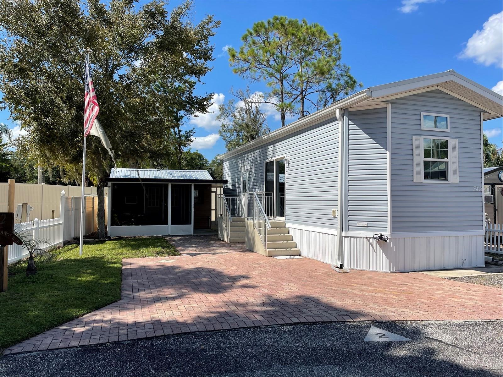 Tiny Homes in Nudist Communities with outdoor living spaces are quite popular these days in Pasco County Florida. This charming Chariot Eagle, HUD approved Hawk Elite park model has the high ceilings with crown molding, rounded corner bead and drywall, extra transom and double pane windows with wood valiance's. This floor plan flows so nicely and every ounce of space is usable. The kitchen has plenty of cabinets, tiled backsplash, recessed lighting, a preparation island that is moveable and a bay window at the South East side. Living room is nice and bright with extra transcom window, decorative crown molding, trey ceiling and sliding glass doors with UV Ray film. The bedroom also conveniently has built in drawers, cabinets, and two closets with mirrored doors. Sconce lighting is on both sides of the bedroom wall. Pocket doors both in bedroom and bathroom provide maximum functional space. Bathroom shower has tiled walls. There is an indoor utility closet with hook up for a stackable washer and dryer but owner opts to have the stand alone washer and dryer in the workshop. The workshop has its own window unit and has electricity and lighting. Extra cabinets and a sink and countertop was installed in the workshop. The screened porch is attached to the workshop. A small private courtyard and outdoor shower with hot and cold water is at the North West side of the property behind the workshop. Another screen enclosure under roof is at the North East side attached to the shed. This is perfect for outdoor exercise equipment or a place for extracurriculars outdoor hobbies. Plenty of pavers on the lot for parking two cars. Flag pole is at the SouthWest end of the property. This property is turn key and is being sold furnished with the television, decor, linens, towels, outdoor furniture, cook and glasswares, and two sheds behind the workshop. Residences enjoy access to the community pool, clubhouse, pavilion, and laundry room. Paradise Pines is a gated nudist community. Only residences and their guests have access to enjoy the amenities. Paradise Pines is within a half mile from Lake Como Nudist Resort, One mile from Paradise Lakes Resort, and 6.5 Miles from Caliente and Bare RV Resort. This community is about 30 minutes from TPA international airport, 40 minutes to an hour from the Gulf of Mexico, and close to shopping and restaurants'. Only 15 minutes to Tampa, minutes from the Suncoast Expressway and I-75.