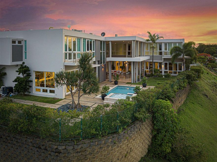 Experience high-altitude living in this stunning Guaynabo residence with breathtaking city and mountain views. Spanning under 10,000 square feet, this expansive home offers unparalleled luxury and features.

Step into this grand home with high ceilings, creating an airy atmosphere. With 7 bedrooms and 6.5 bathrooms, it's perfect for large families or hosting guests. The chef's dream kitchen includes induction stove, and two dishwashers for convenience. A comprehensive security system ensures safety, with cameras inside and outside.

The bedrooms feature built-in desks for studying or creativity. Every bedroom has spacious walk-in closets. Each floor has its own washer and dryer. A spacious maid's room with a bathroom in the first floor for staff or guests. Other highlights include a craft room, sitting room/office, library, and wine cellar.

An attached bonus room with a walk-in closet and full bathroom adds versatility. Formal dining and living rooms create an elegant setting, while the informal dining room and family room offer a cozy atmosphere. Abundant storage spaces are found throughout the property.

Equipped with a generator and water cistern, the property ensures uninterrupted power and water. Enjoy stunning views from balconies and embrace outdoor living with a covered patio and small outdoor kitchen/serving area.

Residents have access to amenities like a swimming pool, tennis court, basketball court, and covered gazebo area. Safety measures include lockable doors and a two-car garage with driveway parking for 5 cars. The pool spa heater and guard fence allow year-round comfort and safety.

Own this exceptional custom-built home in Guaynabo, where luxury, comfort, and breathtaking views converge. Schedule your private showing today and experience high-altitude living at its finest.