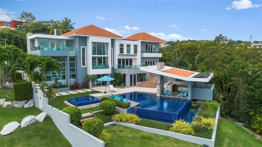 Welcome to 12 and 13 Roble Valley, a private estate within the sought-after Palmas del Mar community in Puerto Rico. This is the only luxury property in Palmas offering complete and permanent privacy, paired with commanding panoramic views of the Caribbean Sea, the surrounding islands, Puerto Rico’s eastern coastline, and the breathtaking El Yunque Rainforest mountain range.

The 5 bedroom, 6 bathroom main residence at 13 Roble Valley is the crown jewel of Palmas del Mar. Paired with the most coveted and breathtaking adjacent lot at 12 Roble Valley, this offering creates a rare opportunity to secure your own private sanctuary, preserved exactly as you wish for years to come.

The home on 13 Roble Valley was completed in 2016 and meticulously maintained by its original and only owners and sits in a category entirely its own. With no neighboring properties to the left or right, every window, terrace, and balcony opens to uninterrupted natural beauty. What you experience here is silence, space, and a sense of seclusion that simply does not exist elsewhere in Palmas del Mar.

The main residence offers five bedrooms, six bathrooms, and approximately 5,000 square feet of refined indoor living. Soaring 13 foot ceilings and expansive custom windows flood the home with natural light and elevate every room with scale and drama.

Only the finest finishes were selected throughout, and each bathroom has been designed as a statement, blending luxury with artistry.

The outdoor living experience is nothing short of extraordinary. The backyard is a private resort, featuring a stunning pool and jacuzzi, a covered BBQ area ideal for entertaining, and a fully equipped indoor gym, all set against a backdrop of lush greenery, ocean views, and open sky, and complemented by a one of a kind outdoor bathroom and shower that allows you to rinse off or unwind while taking in panoramic views of the Caribbean Sea and surrounding islands.

The adjacent lot at 12 Roble Valley has been transformed into a remarkable Greek inspired amphitheater, crafted with 276 one ton boulders to create a serene and magical scene.

With a pergola, fire pit, and storage shed already in place, this space is perfect for gatherings, quiet reflection, or unforgettable evenings under the stars, all while preserving the estate’s unmatched privacy.

This home is as resilient as it is beautiful. Forty one solar panels, three Tesla Powerwalls, a whole house generator, and a 400 gallon rainwater cistern ensure energy independence, security, and peace of mind year round.   

Offered fully furnished and truly turnkey, this estate allows you to step immediately into a lifestyle defined by privacy, elegance, and natural splendor. If you are seeking the rarest offering in the Caribbean, a property that cannot be replicated, 12 and 13 Roble Valley is that opportunity.