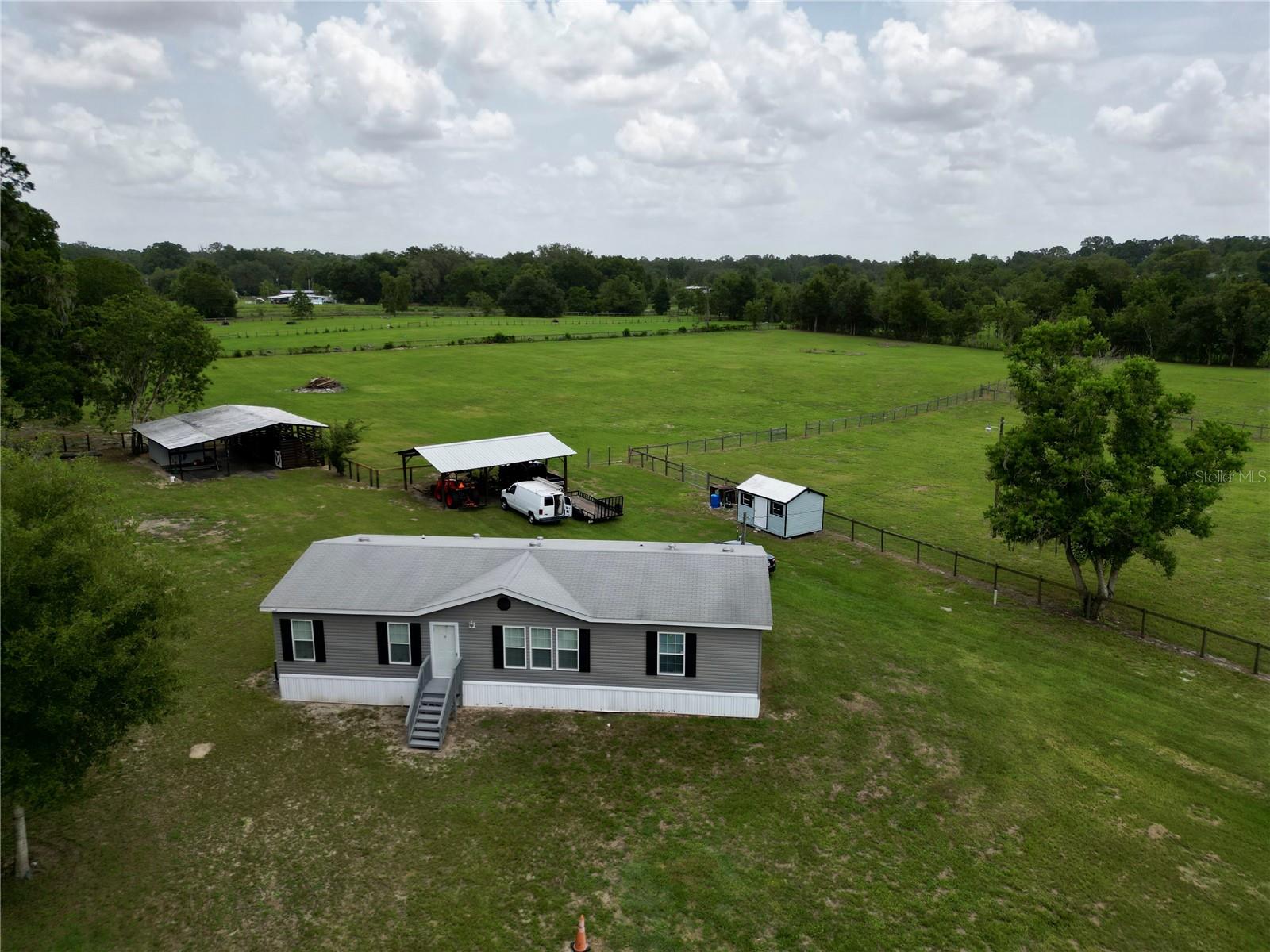 FORE SALE! 5-Acre Equestrian Property with Manufactured Home in Summerfield. This 5-acre A1-zoned property features a 2017-built, 3-bedroom, 2-bath manufactured home with a split-bedroom design and open floor plan. The interior has been freshly repainted, and the property cleared for full usability. Key updates include replaced fencing in select areas, freshly repainted barn and stables, and a recently replaced well tank ensuring dependable water supply. The barn offers four stalls, two wash racks, and an oversized tack room, complemented by a solid 3-car pole barn and an additional storage shed. The property also includes an RV hookup and a spacious back deck overlooking serene views. No HOA or deed restrictions. Conveniently located minutes from The Villages, Florida Horse Park, and the World Equestrian Center.