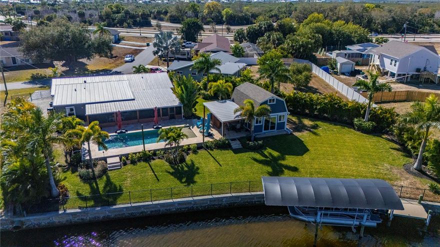 Some homes are designed around rooms, this one is designed around moments. Morning coffee from the screened lanai, afternoons on the water, and evenings that drift from pool to patio without ever checking the clock. Set on a nearly HALF ACRE lot with 129 feet of deep water canal frontage, this coastal contemporary WELL-MAINTAINED home blends refined interiors with relaxed waterfront living, featuring a RESORT STYLE ZERO-ENTRY HEATED POOL, a composite 8x30 dock, and a covered 8,000 lb BOAT LIFT with HARBOR ACCESS in approximately ten minutes. The 2022 added pool serves as the natural gathering point, framed by a cedar lanai and lush professional landscaping with mature trees that create a sense of privacy. Just steps from the pool, a powered 16x24 SHED structure with AC, loft, and its own patio with bar extends the outdoor experience effortlessly, lending itself to an art studio, creative retreat, poolside lounge, man cave, or premium storage. Inside, the chef’s kitchen is thoughtfully designed with beautiful custom cabinetry, expansive solid surface counter space, deep sink, and under cabinet lighting on both upper and lower cabinets. The kitchen opens seamlessly to the living and spacious family rooms, where water views remain the focal point. Custom epoxy flooring delivers an elevated look with easy care durability, while wood plantation shutters accent the impact resistant windows throughout. The primary suite overlooks the canal through sliding doors and serves as a private retreat, featuring an ensuite bath with dual sinks and an elaborate multi head shower with pebble floor for a spa inspired experience. Two spacious guest rooms share an updated bath, while a versatile BONUS ROOM off the family room, currently used as a bedroom, easily functions as a den or office. Notable upgrades include a NEW ROOF in 2023, 2022 four ton AC, full house 24KW GENERATOR, hurricane protection, smart home prewiring for security and doorbell systems, and the peace of mind of no HOA and no flood history. Located in Port Charlotte with convenient access to US 41 and I-75, this home places you minutes from Punta Gorda Airport, Sunseeker Resort, historic downtown Punta Gorda events and dining, local hospitals, shopping, and numerous recreational options including Veterans Park, pickleball and tennis courts, biking and exercise trails, Port Charlotte Beach, and Southwest Florida’s renowned beaches. Waterfront ease, thoughtful upgrades, option to be sold FURNISHED and a location that connects you to it all make this home an exceptional opportunity to enjoy the Florida lifestyle without compromise.