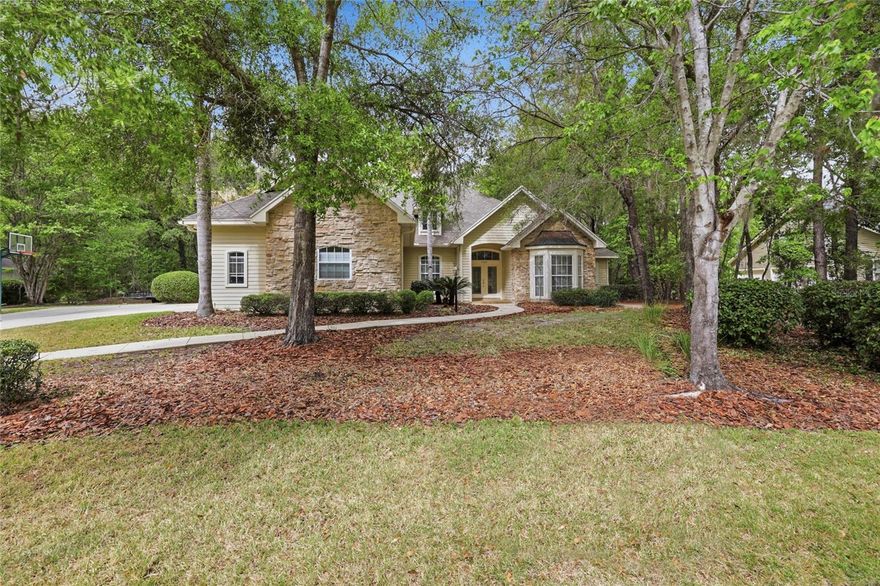 One or more photos have been virtually staged. Majestic oaks and a scattering of palm trees provide the setting for this beautiful five bedroom 4 1/2 bath pool home in Millington subdivisioin of Haile Plantation. The exterior is hardiboard, with stacked stone accents and a large bay window at the front of the home. As you enter the tiled foyer, there is a study to the right, with a high ceiling, a wide bay window and a large storage closet. The dining room is to the left of the entry foyer, with a high ceiling and windows that look out to the front yard. The formal living room has wood floors and French doors that lead to the screened pool deck. The kitchen has wood cabinets, some with glass fronts, granite countertops, a central island and a long breakfast bar that can accommodate six for quick meals and snacks. The stainless-steel appliances include a side-by-side KitchenAid refrigerator/freezer, with a water and ice dispenser, a KitchenAid wall oven, with a microwave above, a KitchenAid dishwasher, and a double stainless-steel sink, with a gooseneck faucet.  Adjacent to the kitchen is a light-filled breakfast area, surrounded by windows that reveal a view of the pool. The family room has a soaring ceiling and a wood-burning fireplace, flanked on either side by cathedral-shaped windows and built-in storage cabinets. The principal bedroom has French doors that open onto the pool area. The adjacent bathroom has double sinks and vanities, a stall shower, an enclosed WC and an oval shaped jetted tub, with a glass block window above to usher in natural light. A huge walk-in closet provides ample hanging and shelf space on multiple racks. Three more bedrooms are on the first floor, with two sharing a Jack and Jill bath and one having its own private bath. The laundry room is conveniently located adjacent to these bedrooms and has a Kenmore washer and dryer, a large soaking sink, cabinets for storing cleaning supplies and a built-in ironing board. Stairs lead up to the fifth bedroom, which could also be a home office or playroom, with an expansive closet and a bathroom with a stall shower. Crown molding adds a note of elegance to the décor and most of the rooms have paddle fans and recessed can lighting. The screen pool and spa are surrounded by lush landscaping and views of the woods. The three-car garage offers additional storage space and the house got a new roof in 2024 and a new HVAC unit in 2021. The extensive trail system and tree-lined streets of Haile Plantation provide many areas for walking and biking. The Village Center is conveniently located to Millington, for strolling, dining and shopping. Hawkstone Country Club offers several levels of membership for those interested in tennis, golf or the fitness center.  The University of Florida, the UF Medical Center, North Florida Regional Medical Center and several parks and nature preserves are all with a short drive of Haile Plantation.