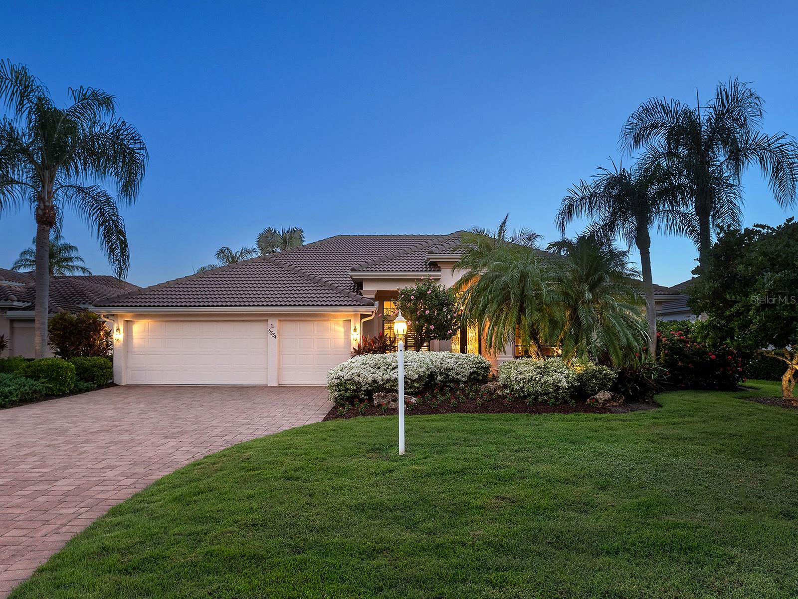 Set on a beautifully landscaped homesite within the gates of Lakewood Ranch Country Club, this meticulously maintained residence offers 3 beds and 3 full baths. From the moment you arrive, the home makes an elegant impression with its oversized paver driveway, gorgeous landscaping, with lighting that enhances its curb appeal. A tile roof, three-car garage, and a paver walkway leading to the glass-detailed front doors complete the inviting approach. Inside, the foyer welcomes you with crown molding, a chandelier, and ceramic tile floors, introducing a layout designed for both comfort and entertaining. The formal living room features pocketing sliders topped with transom windows, flooding the space with natural light, while the adjoining dining room offers a defined setting with a niche for a credenza, plantation-shuttered windows, and a pony wall with a column accent. The kitchen is a highlight of the home, spacious, functional, and thoughtfully designed with abundant solid-wood cabinetry, a large bar-height counter with granite top, and a coordinating dry bar featuring glass display cabinets, tumbled-stone backsplash, and accent lighting above and below. Stainless-steel appliances include a Frigidaire gas range, Samsung microwave, Whirlpool refrigerator, and a newer stainless apron sink. Additional features include a workspace area with a granite countertop, a hallway pantry, and an aquarium window framing the breakfast nook. Open to the kitchen, the family room provides an ideal gathering space with custom ceilings, built-in speakers, crown molding, and custom built-ins with bench seating on either side of the media wall. The functional floor plan ensures privacy for all. The primary suite is an expansive retreat featuring two sets of pocketing sliders to the lanai, plantation shutters throughout, a generous seating area, a walk-in closet and a wall closet, each outfitted with built-ins. The en-suite bath includes dual vanities (one with a makeup area), a sunken tub set beneath a glass-block privacy window, a walk-in shower with seamless glass, tile flooring, a private water closet, and a drop-down soffit ceiling detail. Two additional guest rooms offer comfort. One is designed as a guest suite with direct lanai access, a custom closet, and a stunningly remodeled en-suite bath featuring a designer lighted mirror, walk-in shower with bench seating, and a linen cabinet. The other guest bedroom is complete with a wall-to-wall shelf and a spacious closet, located near a well-appointed full bath. The guest full bath includes a spacious vanity with solid-surface counters and a tub/shower combination. A separate office with built-in floating shelves, detailed trim, and a full closet allows for use as a fourth bedroom if desired. Outside, the expansive screened lanai embodies the Florida lifestyle. With a cool-deck surface, remote-controlled awning, two covered seating areas for dining and lounging, and ceiling fans for comfort, the space overlooks a sparkling pool and spa. The outdoor kitchen includes a refrigerator, sink, and designated grill area, while lush tropical landscaping frames the scenic backyard and provides a sense of privacy. With the addition of a fourth course, Lakewood Ranch Golf and Country Club offers unparalleled access to premier golf and a variety of membership options. Ideally located just minutes from Waterside, UTC, and Main Street, the home is also convenient to dining, shopping, and world-class beaches.