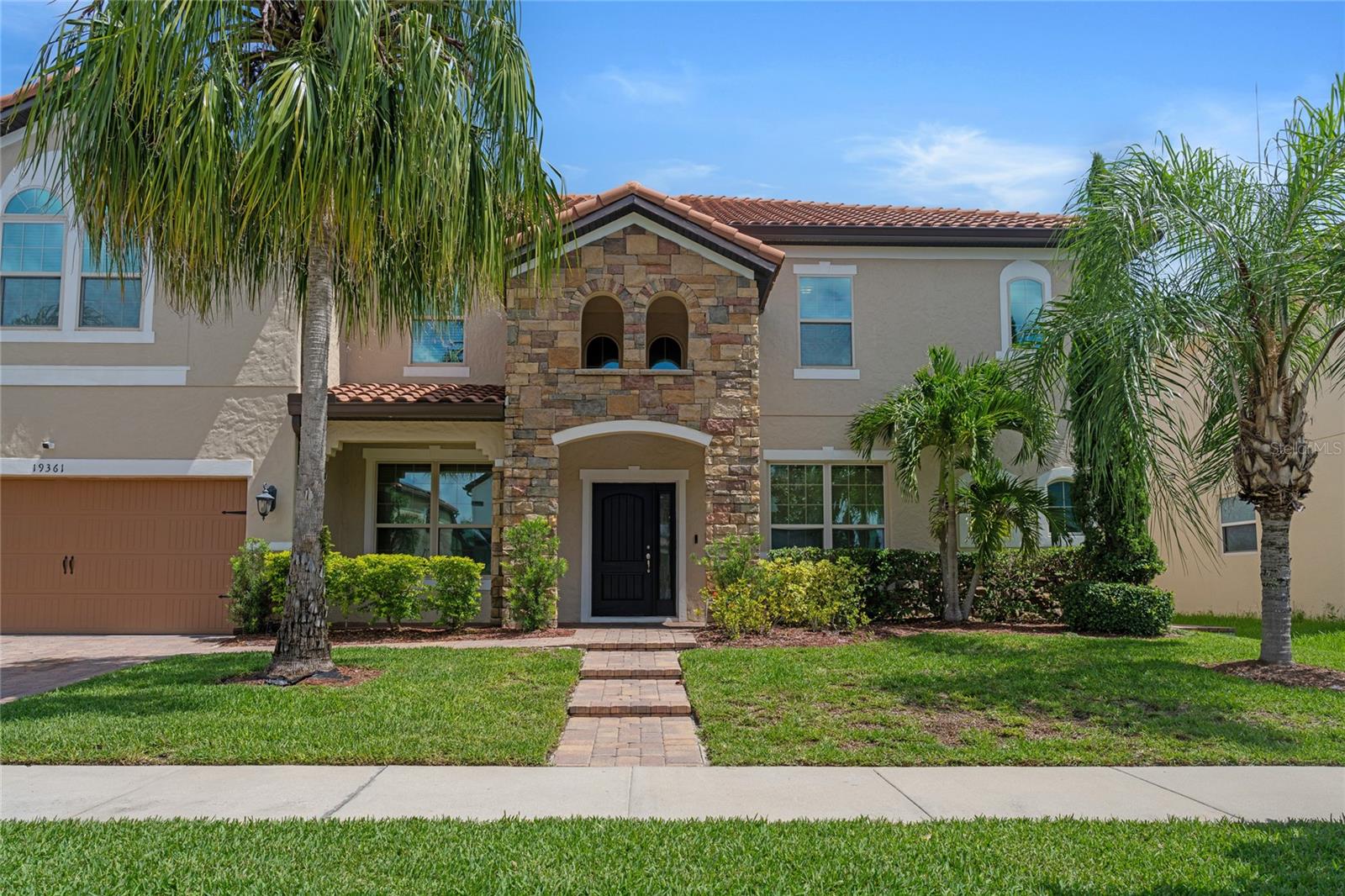 Welcome to 19361 Pummelo Drive, an impressive 6-bedroom, 6-bathroom luxury residence nestled in the highly desired community of Fells Landing in Lake Nona. Boasting just under 4,700 square feet of beautifully designed living space, this home offers the perfect balance of comfort, functionality, and elevated style. From the moment you arrive, you'll be struck by the massive, elegant homes that line Pummelo Drive — a quiet, upscale street that showcases the best of Fells Landing living. This residence stands out with its grand curb appeal, welcoming covered front porch, and thoughtfully upgraded interior finishes throughout. Step inside to an expansive open floor plan featuring designer accent walls, custom lighting, and a seamless flow ideal for both entertaining and everyday living. The gourmet kitchen is a chef’s dream, with granite countertops, a spacious island, stainless steel appliances, and ample cabinetry, all overlooking a bright and airy living and dining area. This home is ideal for multi-generational living with two bedrooms and two full bathrooms on the first floor, while the second level offers four additional bedrooms, a generous loft, and a home theater — perfect for movie nights or game days. The primary suite features a spa-inspired en-suite bathroom and an oversized walk-in closet. Enjoy the convenience of a downstairs laundry room, a 3-car garage, and plenty of storage throughout. Step outside to a private backyard ready for entertaining or quiet evenings. Residents of Fells Landing enjoy the serenity of a well-maintained community with beautifully crafted homes, manicured landscaping, and easy access to Lake Nona’s top destinations — including Medical City, Lake Nona Town Center, Boxi Park, top-rated schools, shopping, dining, and major highways. This is luxury living in one of Orlando’s most desirable neighborhoods — come experience it for yourself.