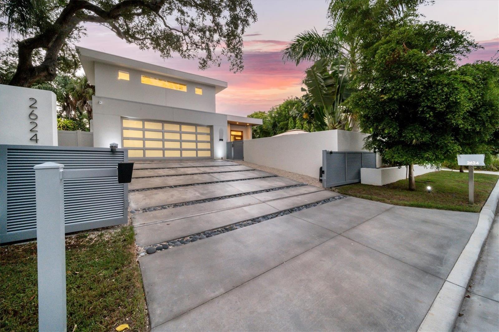 One or more photo(s) has been virtually staged. Award-winning architect Mark Sultana’s modern design, a highly desirable WEST of TRAIL location, and top-quality Voigt Brothers construction are just a few of the reasons this 5 bedroom, 5 bath, pool home built in 2021 is exceptional. Propped high on a charming street and not in a flood zone, this private and walled property opens to a large Palm Springs style terrace with saltwater heated Pebble Tec pool, spa, sun shelf and fire pit, perfect for cocktails and intimate conversation or entertaining a crowd. Enjoy the Florida lifestyle at its best in a bright and open floor plan with 13’ high ceilings flowing from the front door to the back patio through a wall of glass. Disappearing glass doors open to your private tropical back yard and summer kitchen- with plenty of room to entertain, dine, throw a ball or play with the dog. The living room floor-to-ceiling accent wall features an electric fireplace and is flanked by floating solid oak shelves with undermount lighting. A sleek chef’s kitchen is centered on a dramatic 14-foot double thick island with waterfall and seating space for six. Five ultra-premium DACOR appliances are complemented by solid wood custom cabinetry, with, a wine cooler, and variable accent lighting. The dining room has 10’ windows overlooking the pool terrace and is discretely separated from the kitchen by an accent wall with LED lighting. The first-floor owner’s suite has a glass door to the terrace, two walk-in custom closets, a spa shower, freestanding tub, separate water closet and a floating vanity with undermount lighting. The second floor features a loft office, and two bedrooms including a second primary suite. Also on the second level is a large flex room with full bath and walk in closet, a wet bar, surround sound and an AV closet-perfect for a media room, another large bedroom or playroom. You’ll find the 5th bedroom on the first floor along with a bathroom, and a large laundry room with utility sink, storage and garage access. The owners spared no expense equipping this home: wide plank French oak hardwood floors, cypress wood outdoor ceilings, a 20 KW Kohler whole-house generator supplied by two propane tanks which are also connected to the 2 tankless water heaters, the kitchen stove and pool heater. Two 15 SEER HVAC units. All concrete surfaces have a non-slip coating. There’s a privacy wall and fence, a motorized security gate, impact windows, doors and an impact garage door all connected to a Smart home system which also controls lighting, sound, TVs, window shades, cameras and the pool. Commercial grade membrane roof. This is a fabulous meticulously crafted residence located minutes from world-renown Siesta Key Beach, quaint Southside Village, downtown dining, galleries and boutiques and the rich cultural life of Sarasota with opera, ballet, theatre and festivals in a charming city of 58,000. You will be two blocks from an adorable playground at one of the highest rated elementary schools in the district. Don’t miss out! WATCH THE VIDEO!
