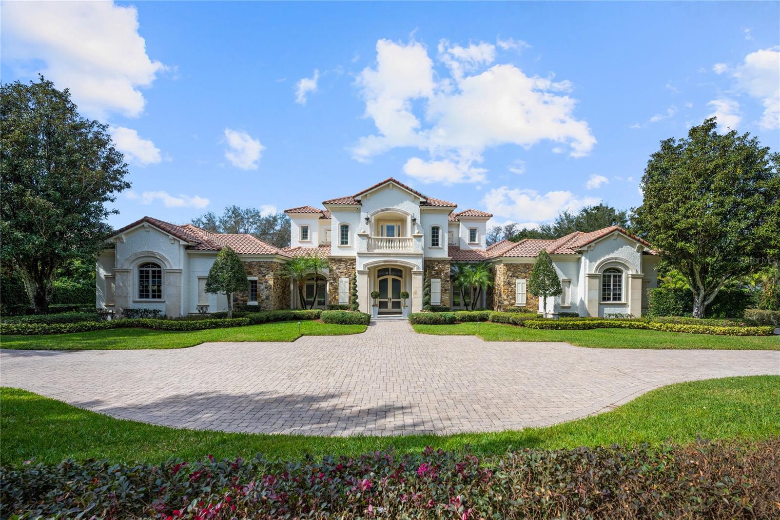 Under contract-accepting backup offers. Nestled within the highly sought after, guard-gated community of Lake Butler Sound, this breathtaking lakefront estate has been completely remodeled with designer interior and exterior finishes, offering an unparalleled blend of sophistication and modern luxury. Positioned on an expansive corner lot, this home boasts breathtaking panoramic lake views from nearly every room, creating a serene and picturesque setting for the most discerning buyer. Step inside to discover impeccable craftsmanship and exquisite architectural details throughout. The primary suite is a private retreat, featuring an elegant sitting area, a two-story custom closet, and a spa-inspired bath with an oversized soaking tub, a luxurious walk-in shower overlooking a private courtyard, and exquisite designer finishes that elevate the experience of relaxation. The gourmet kitchen is a chef’s dream, outfitted with top-of-the-line appliances, a large center island with a separate prep sink, a hidden pantry, stunning marble countertops and a marble back splash that showcase both beauty and function. This culinary space seamlessly flows into the open living and entertaining areas, where you’ll find a first-floor home theater, a wine cellar, a home gym/ 6th bedroom, and a stunning game room with dramatic arched ceilings and a wall of windows that frame breathtaking lakefront vistas. The second-floor features three luxurious en-suite bedrooms, a spacious lounge area, and a sprawling balcony that overlooks the resort-style pool and the shimmering waters of Lake Butler. The outdoor spaces are equally captivating, with lush landscaping, multiple covered patio areas for alfresco dining, a summer kitchen, a triple gas fire pit, and an extraordinary resort-style pool complete with a hot tub, stair-stepped waterfall feature, and a travertine marble patio. At the water’s edge, an expansive private boat dock provides direct access to the renowned Butler Chain of Lakes, perfect for boating, fishing, and water sports enthusiasts. With every detail thoughtfully curated and no expense spared, this remodeled masterpiece is the pinnacle of lakefront luxury living.