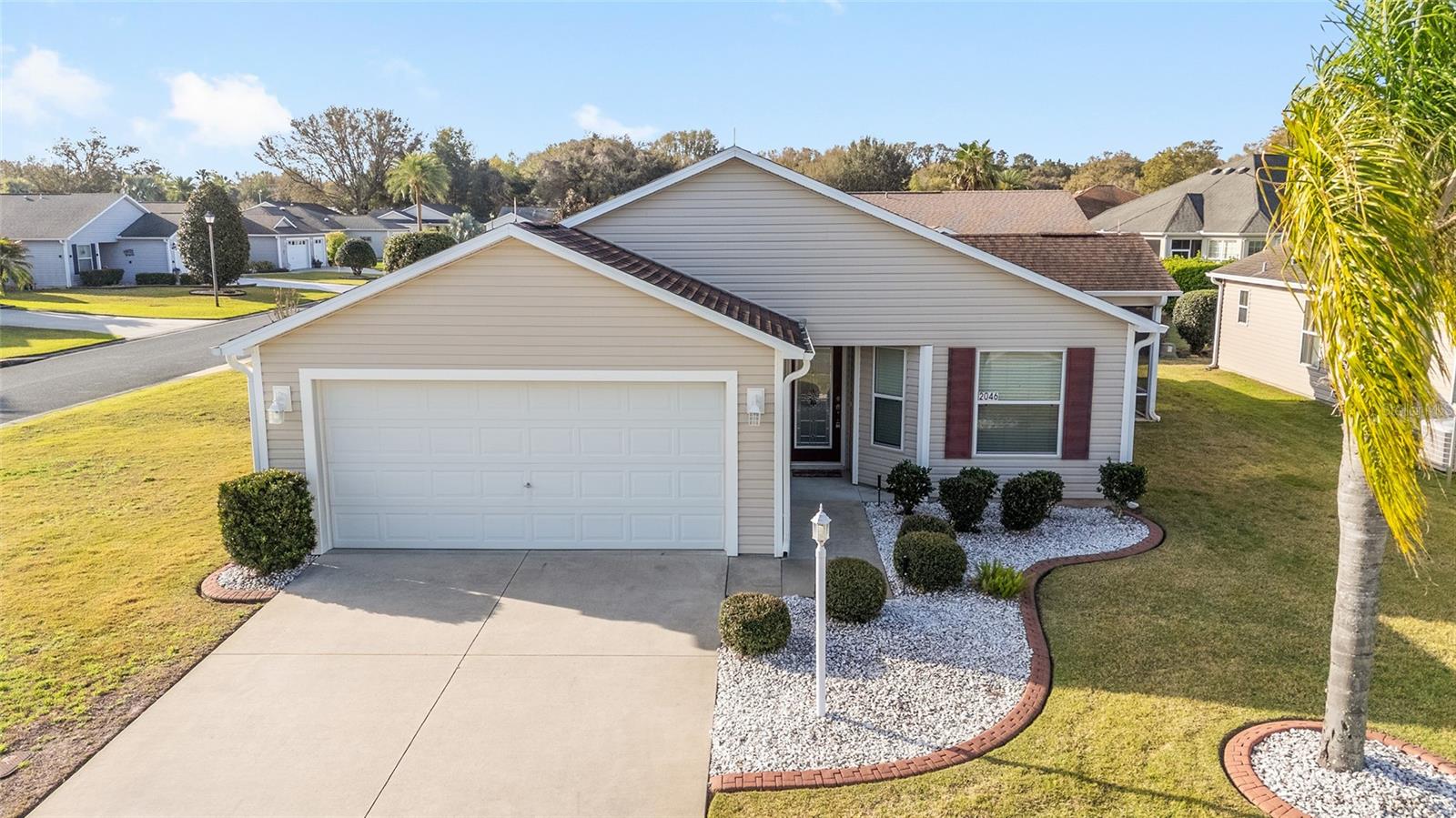 One or more photo(s) has been virtually staged. BOND PAID! BRAND NEW ROOF! BRAND NEW HOT WATER HEATER! LOW SUMTER TAXES! HOME WARRANTY INCLUDED! Welcome to this beautifully well-maintained AT-EASE Cottage model, offering comfort, updates, and a prime location in the heart of The Villages (between CR466 and CR466A). This bright and spacious home features vaulted ceilings throughout (no popcorn ceilings) and a freshly painted interior accent walls. Tile flooring flows seamlessly through the home, while the eat-in kitchen offers abundant cabinet space with pull-outs, a pantry closet, and sliding doors that open to the screened lanai. The primary suite boasts a large walk-in closet and an en suite bath with dual sinks and a custom Jetta Stone walk-in shower. The second bedroom sits conveniently near the guest bath—perfect for visitors. The third bedroom, located at the front of the home, provides flexibility as a guest room or home office. All bedrooms have closets. Step outside to the roofed, screened lanai with privacy shades and a concrete patio (ideal for an added birdcage). The corner lot adds privacy and space as well as beauty. The two-car garage and indoor laundry complete the thoughtful design. Close to shopping, rec centers, golf, pools, country clubs, restaurants - and more! Schedule your showing today!