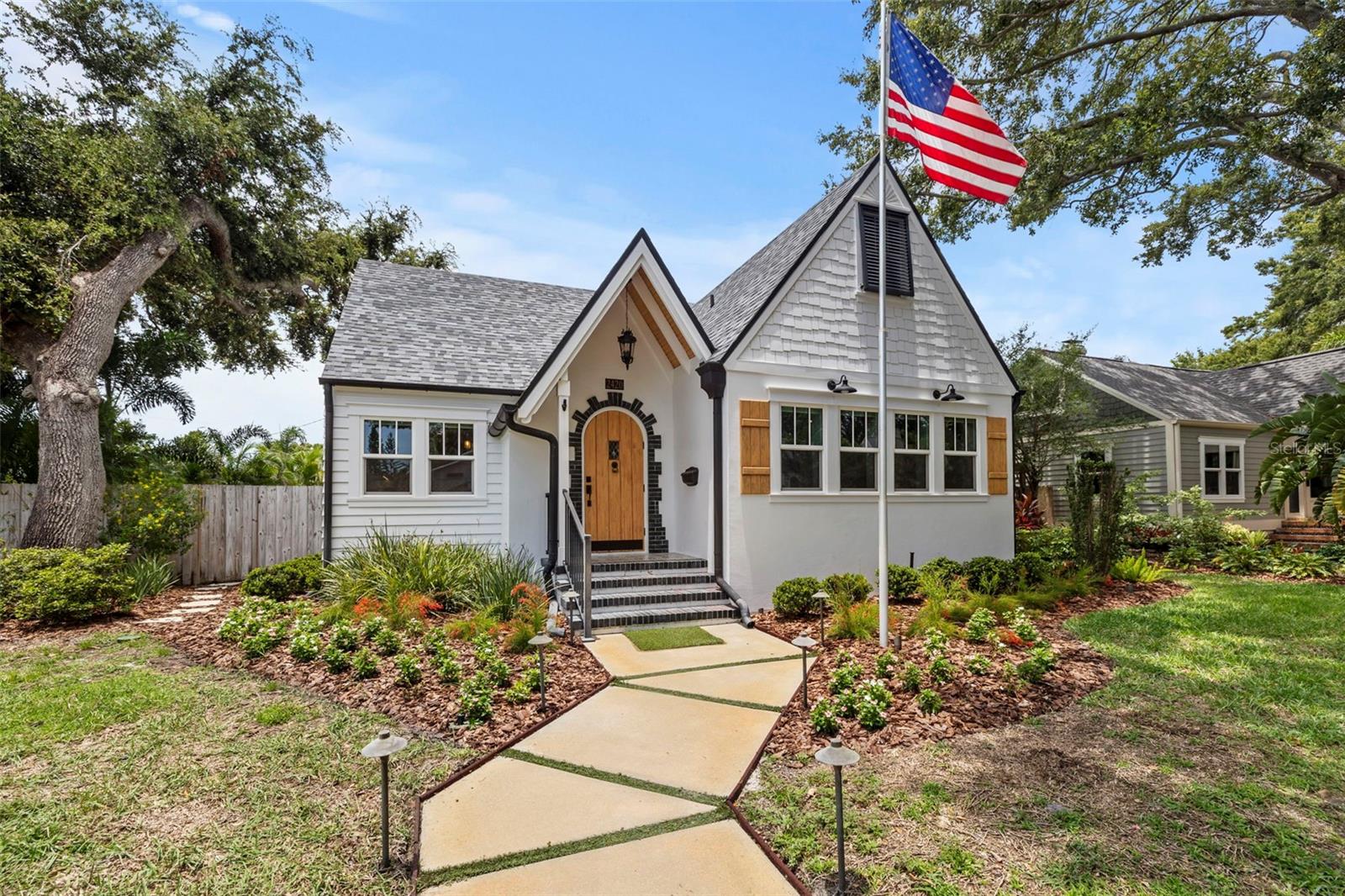 Once upon a time, the perfect home on the perfect street in the heart of Sunshine City became available—and it could be yours. Nestled in the highly sought-after, high-and-dry (non-flood zone) neighborhood of Woodlawn, this meticulously restored Tudor-style masterpiece blends timeless charm with modern luxury. Situated on an oversized 110x69 lot, this five-bedroom home plus dedicated office and three full baths offers nearly 3,000 square feet of heated and cooled living space—plus an air-conditioned two-car detached garage with a loft (not included in the square footage). Every major system has been thoughtfully upgraded since 2019, including hurricane-impact windows, new roof, HVAC, whole house plumbing, whole house electrical, siding, insulation, gas lines, and even a generator plug—leaving nothing for you to do but move in.
From the storybook lawn to the original arched wood front door, this home radiates curb appeal. Inside, European hardwood floors lead you through light-filled, inviting spaces, including a show-stopping award winning kitchen: custom solid wood cabinetry, quartz countertops, gas range with custom hood, double ovens, coffered ceilings, oversized island, brushed gold fixtures, TWO pantries, and a farmhouse sink. The expansive living room features custom wainscoting, recessed lighting, and a whole-house Sonos system—indoors and out—making it the perfect space for effortless entertaining.
The spacious primary suite is conveniently located on the main level and features tray ceilings, a large walk-in closet, and a beautifully updated ensuite with a walk-in shower. Continuing our tour of the downstairs, a split floorplan offers privacy, second bedroom, full bath, and dedicated office. Upstairs, you’ll find three additional bedrooms, a full bath, a versatile loft space perfect for a second office or media area and oversized air conditioned storage closets that run the full length of the upstairs! Perfect for those storage items you want to keep protected but out of sight: holiday decorations, photos, seasonal items etc.
Step outside to your backyard oasis with a brand-new Trex deck, gooseneck lighting, and NEW siding. With plenty of room for a pool and still space to play, the fully fenced yard is ideal for families, pets, and gatherings. Additional features include alley access, ample off-street parking, and a rare sense of privacy in the middle of it all.
Located in the heart of Woodlawn Circle, you’re just steps from Trip’s Diner, local coffee shops, and neighborhood favorites—or hop on your bike and head downtown to the St. Pete Pier, Saturday markets, and world-class dining. Just minutes to award-winning Gulf beaches, parks, top-rated schools, and Tampa International Airport. Dreams really do come true at 2420 14th St N. Schedule your private showing today and make your happily ever after a reality!