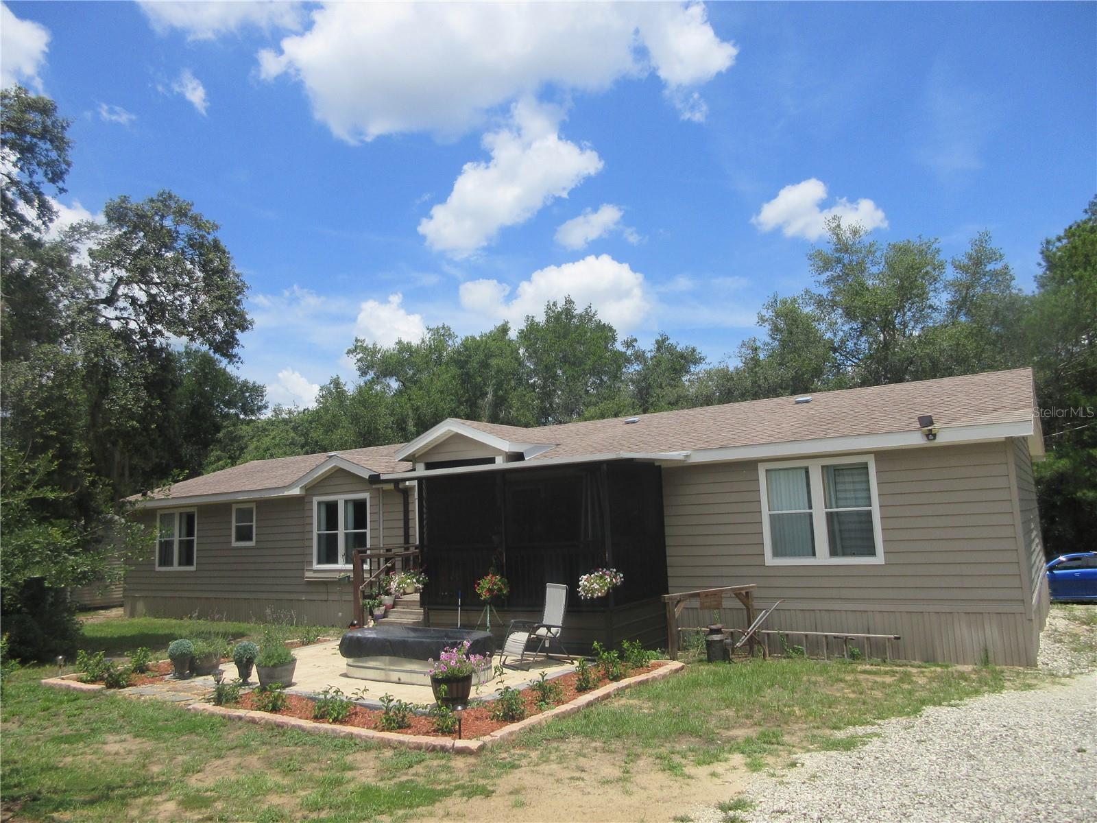 Peaceful Country Living on 3 Acres! NEW ROOF IN JULY 2025! Welcome to your private Oasis in the heart of nature! Nestled on a serene 3 acre A-1 zoned flag lot, this well maintained 2-bedroom 2-bath 2006 Doublewide home offers 2,136 sq ft of spacious living and is perfect for those seeking peace, privacy, and plenty of room to roam. A brand-new architectural shingle roof in July 2025, adding long-term value and peace of mind. Additional recent upgrades per Seller include New 4” well (2022) 140 ft deep, New 4-ton AC unit (2018) – serviced and refurbished in 2025, Updated electrical work (June 2025), New metal handicap-accessible ramp with 2-tier platform (2023), 2024 septic risers for easy access (last pumped 2023). Step inside to find an open floor plan, soaring high ceilings, and a spacious living and dining area perfect for entertaining. The large kitchen features stainless steel appliances, stylish track lighting, ample cabinet space with open shelving, a pantry, and a breakfast bar. The oversized master suite includes a luxurious master bath with dual sinks, a garden tub, tiled shower, and a massive walk-in closet. The guest bedroom is also generously sized with a walk-in closet, plus there's a bonus room ideal for an office, nursery, or third bedroom. Enjoy outdoor living with a screened 19x6 front porch, Stone patio surrounded by lush flowers, 10x10 jasmine-covered pergola, 24x36 three-stall horse barn (roof needs repair), 20x18 detached metal garage, 21x12 metal carport, 15x12 shed, 9x9 storage shed, spacious chicken coop, three 250-gallon water containers along with a fully fenced property with separate fenced areas for animals or horses. Just a short walk to Wells Pond and Lake Bryant Fish Camp, with public boat ramp access for fishing or boating. You’re also just 15 minutes to Ocklawaha River Boat Ramp and Silver Springs State Park, and only 1 hour to Daytona Beach! Located in the heart of the Ocala National Forest, enjoy access to nearly half a million acres of outdoor adventure, including 600 lakes, rivers, springs, hunting, hiking, horseback riding, camping, and world-class ATV trails. Whether you're a homesteader, horse lover, nature enthusiast, or simply want more space and freedom, this move-in ready property offers it all! Don’t miss out on this slice of country paradise.