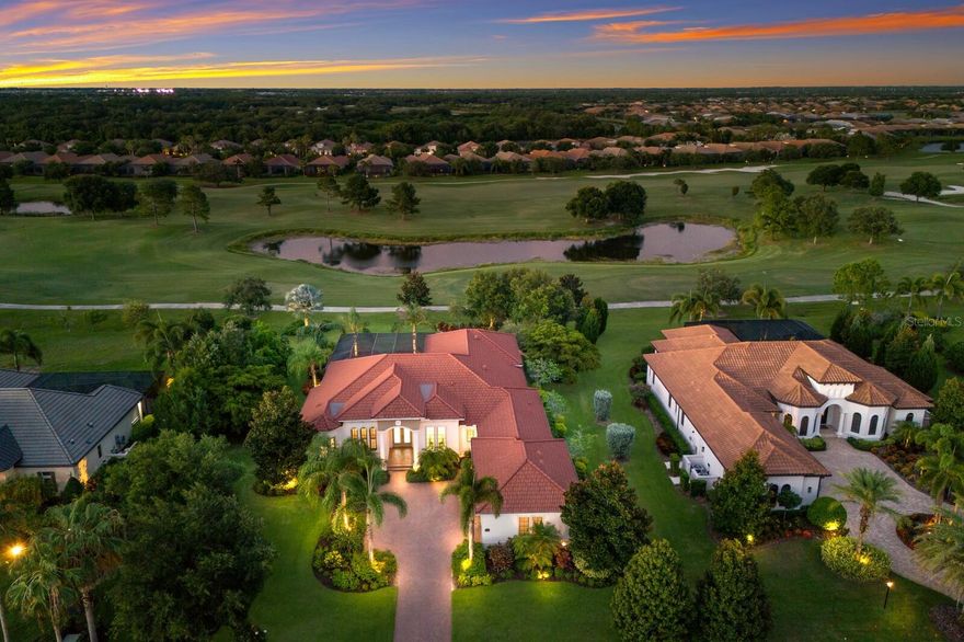 The pinnacle of luxury living on the most impressive street in Lakewood Ranch's Country Club East. This remarkable 3736 square foot SINGLE STORY John Cannon built home sits majestically near the end of the cul-d-sac on a sprawling 220ft by 125ft site and is perfectly positioned on the 5th tee of the Royal Lakes golf course.  The raised elevation and maximum allowable setback from the street creates a striking first impression, setting the tone for the elegance within. As you step inside, the impact sliding glass doors pocket completely out of sight, revealing uninterrupted vistas of the large yard, lush surroundings, golf course and serene pond. The interior features a neutral great room plan with soaring 12-14 foot ceilings centered around a contemporary cast stone fireplace, ideal for both relaxation and entertaining. Every detail exudes quality and sophistication throughout this home. No expense has been spared in the large custom kitchen, with commercial level gas appliances, substantial hood system, double ultra quiet Bosch dishwashers, a large hidden pantry, and a wine bar equipped with a duo temp wine cooler, and a clear ice machine. For the ultimate comfort and convenience, the residence boasts a sound system throughout, four-zoned AC climate control, and all 4 bedrooms feature 8 foot doors, walk-in closets, and direct access to bathrooms. A massive bonus room provides additional flexibility for living and entertaining and seamlessly merges with the exterior. From there, step outside to discover an entertainer's paradise with a spacious covered deck and an outdoor terrace with no detail overlooked. Enjoy a large heated pool and spa year round or gather around the natural gas fire pit under the stars.  Dining al fresco will be a part of life here as your new home features a full-service summer kitchen, complete with a 42-inch Lynx grill system, ample refrigeration, sink, and even a kegerator. This home represents a rare opportunity to experience the finest in Florida living, combining luxurious amenities with an unparalleled location and breathtaking views. Embrace the lifestyle you deserve in this extraordinary residence on Country Club East's most coveted street, Camargo Place.