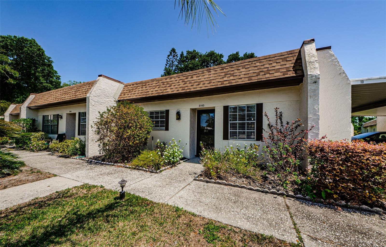 **FORMER MODEL**Don’t miss this beautifully remodeled and incredibly affordable 2-bedroom end-unit villa in Highland Lakes, Palm Harbor’s premier 55+ golf community. This charming condo features a bright open floor plan with a brand-new kitchen, complete with built-in coffee bar, a bonus sunroom, and generous closet space throughout. Located just steps from your assigned carport—with extra storage and space to park and charge a golf cart—convenience is built right in. The Mission Grove neighborhood clubhouse, complete with a pool and laundry facilities, is only a short walk away across the parking lot. Best of all, there’s no land lease, and your purchase includes membership to Highland Lakes, offering free green fees on three private executive golf courses. The community’s incredible amenities also include tennis and pickleball courts, an Olympic-sized heated pool and spa, a vibrant main clubhouse with an auditorium, pickleball/tennis/bocce ball, arts and crafts studios, a woodworking shop, and a packed calendar of entertainment, social events, and fitness programs. Residents also enjoy access to the Lake Tarpon Lodge, featuring another heated pool, party pavilion, fishing pier, community pontoon boats, and even RV or boat storage with a private ramp and dock for a nominal $25 a year. Located just minutes from Gulf Coast beaches, shopping, dining, professional sports venues, cultural attractions, two airports, and a cruise port, this home is ideal as a year-round residence or a seasonal getaway. HOA/Condo fees cover water/sewer/trash, cable/internet, insurance on the building, exterior maintenance, roof, and maintenance of the grounds. ***Electric panel replaced in 2023, kitchen and bathroom 2025, brand new flooring throughout, water heater 2025, refrigerator and dishwasher 2025***No milestone needed! High and dry: Non-Evacuation zone!