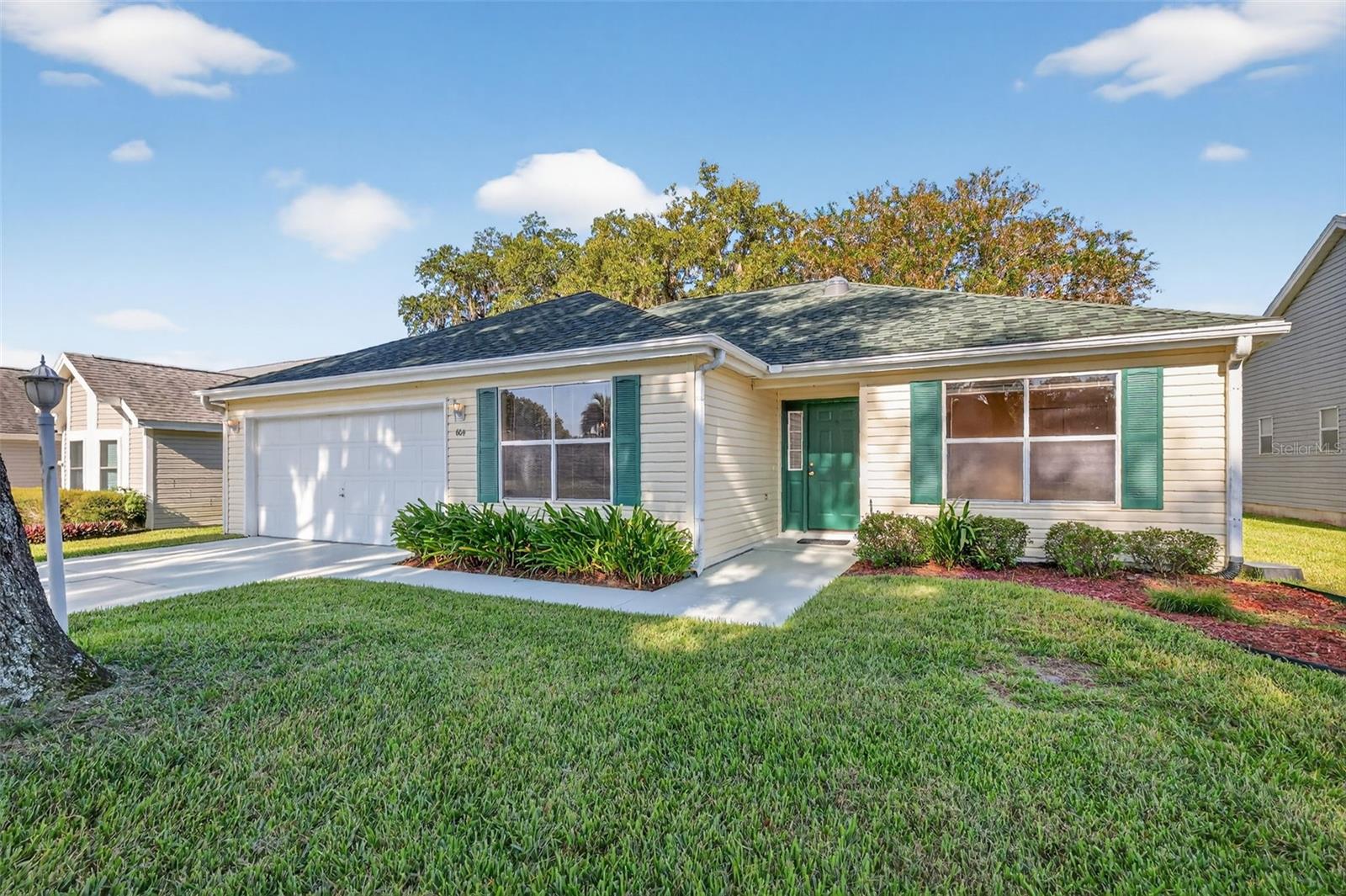 One or more photo(s) has been virtually staged. BEAUTIFUL 3/2 Wisteria (Jasmine) with ENCLOSED LANAI, and REAR PATIO - JUST MINUTES to BOTH Spanish Springs Town Square and Lake Sumter Landing in the charming Village of DeLaVista! BOND PAID!  METICULOUSLY-MANICURED landscaping, GORGEOUS oaks, a COVERED entry vestibule, and front door with SIDE LITE welcome you in to the GENEROUS, TILED foyer of this INCREDIBLE home! The AMAZING kitchen features an ABUNDANCE of RICH, WOOD CABINETRY; LUXURIOUS CORIAN counters; DOUBLE built-in PANTRY; BRAND NEW, NEUTRAL-TONED TILE flooring; and a CONVENIENT pass-thru window that connects the kitchen to the living and dining areas. Its ADJACENT DINETTE features two large windows for ABUNDANT NATURAL LIGHT. Soaring VAULTED ceilings, grace the EXPANSIVE OPEN-CONCEPT living and dining areas. STUNNING HARDWOOD FLOORING adorns these rooms adding a touch of ELEGANCE and SOPHISTICATION. The formal dining room boasts a MODERN chandelier and a large SOLAR TUBE that adds additional light. From the living room, sliding glass doors lead to an ENCLOSED LANAI with a plethora of windows and an adjoining REAR PATIO. Both of theses areas showcase decoratively painted floors and create the IDEAL SPACE for hosting gatherings or simply relaxing with friends and family! Back inside, the primary bedroom features RICH, HARDWOOD flooring, a generous WALK-IN closet, and sliding glass doors that open to the lanai. Its en-suite bathroom offers WOOD cabinetry, DOUBLE sinks, WALK-IN shower, TILE floors, and a LINEN closet. A SPLIT FLOOR PLAN with two additional bedrooms and a second bathroom ensure plenty of PRIVACY for guests or a quiet home office. Bedrooms two and three both offer HARDWOOD floors, DOUBLE windows, and built in closets. The second bathroom features a WOOD vanity, a tub and shower combination, TILE flooring, and a hallway LINEN closet. A centrally located INTERIOR LAUNDRY ROOM boasts additional shelving and a LARGE hallway STORAGE closet. The TWO CAR garage completes the package and features an EPOXIED floor and PLENTY of room for parking and storage! DON’T MISS YOUR OPPORTUNITY TO MAKE THIS WONDERFUL HOME YOUR OWN! Located in the heart of the Village of De La Vista, this home is JUST MINUTES from BOTH Lake Sumter Landing and Spanish Springs Town Square! Close to Tierra Del Sol and Glenview Country Clubs and Championship Golf Courses; De La Vista and Mira Mesa Executive Golf Courses; Hacienda Regional Recreation Center; numerous neighborhood pools, pickle ball, and multiple other activities; the Villages Regional Hospital; and HWY 441/27 and CR 466 with an abundance of shopping, dining, banking, medical and more! PLEASE WATCH OUR WALKTHROUGH VIDEO of this INCREDIBLE HOME, and call today to schedule your Private Showing or Virtual Tour!