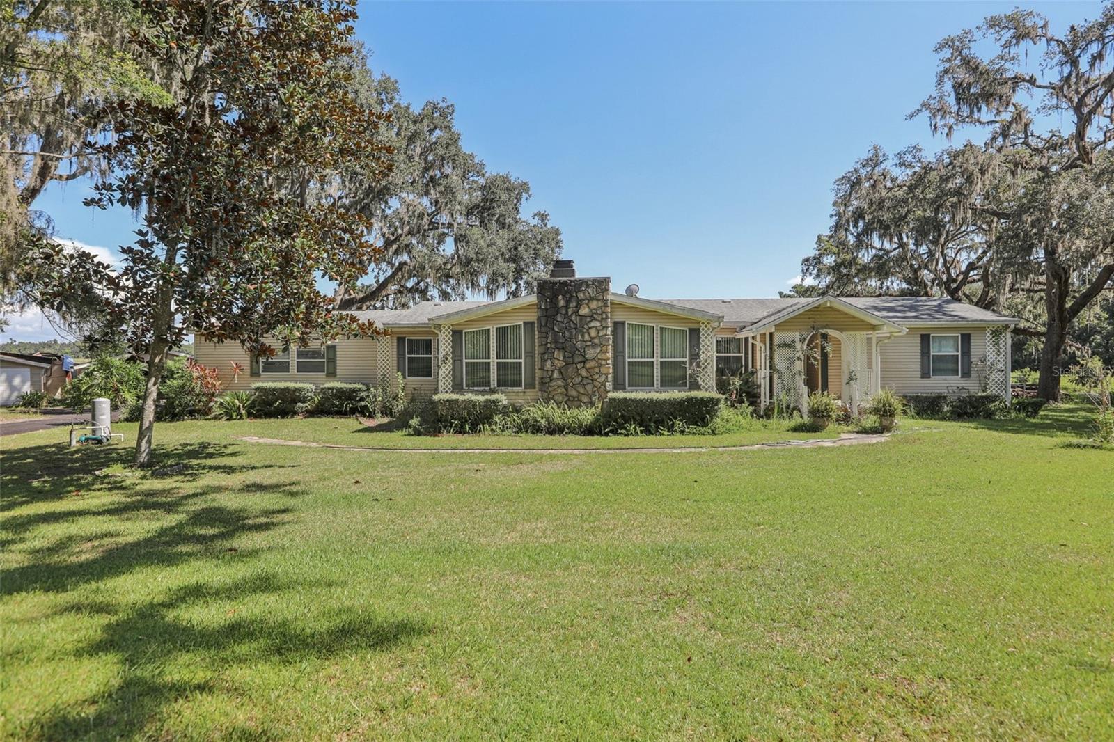 Discover your private country estate at 29235 Bayhead Rd, Dade City, Florida. This stunning Palm Harbor homes model ranch-style mobile home is situated on a spacious 5.58-acre lot, offering the perfect blend of tranquility and convenience for families seeking ample space and the joys of country living.
The main residence features 3 bedrooms and 2 bathrooms, including a formal living room and dining room showcasing beautiful travertine stone tiles, along with a cozy family room complete with a fireplace. This home has many recent updates, boasting a roof installed on the main house in December 2017, gutters with a leaf filter system added in 2022, and a newly paved driveway completed in 2024 and coated in 2025. For your convenience and peace of mind, the property also includes garage door openers, hurricane coverings for all windows, and an upgraded water filtration system installed in July 2025. Additional recent maintenance includes a septic drain field replacement in June 2018 and a cleaning in 2023. The property is further enhanced by majestic mature oak trees and Southern magnolias, creating a picturesque setting.
Beyond the main home, the property offers several valuable outbuildings. A second building spanning 960 sq ft includes 2 bedrooms, 1 bathroom, a delightful sunroom, and features a new roof completed in 2024. A third building, also 960 sq ft, presents the potential for conversion into additional living space, while a 2000 sq ft concrete barn features a large workshop, high ceilings, and two convenient storage rooms. The expansive garage space can accommodate up to 6 cars, and could easily be converted into horse stables, catering to equestrian enthusiasts. This property is eligible for USDA loans, making it an attractive option for qualified buyers, and is being sold "as-is".
This exceptional estate provides an idyllic setting for families to grow, thrive, and create lasting memories. This unique property offers a competitive opportunity in the current market. Don't miss out on the chance to call this magnificent estate your home! Contact us today to schedule your private showing.