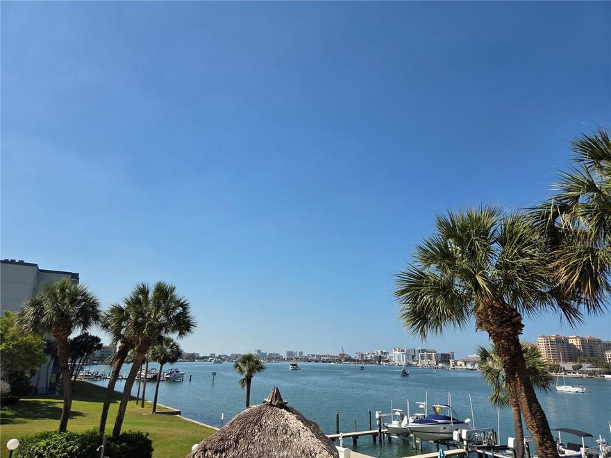 Live the island life you have always envisioned in this waterfront condominium located in the coveted community of Island Estates. This second floor condo is perfectly situated, showcasing sweeping southwest open water views across the Mandalay Channel towards Clearwater Beach. The over-sized 23 foot balcony is perfect for enjoying the world-famous sunsets and gentle gulf breezes. The home has been outfitted with newer impact resistance sliders and windows in the living room and primary suite, second bedroom and kitchen, providing both peace of mind and beautiful sight lines, connecting the spectacular outdoor views with the living space. As you enter, you are immediately drawn towards the centerpiece panoramic water views and natural light that pour in. The primary suite is generously sized, offering water views, balcony access and an en-suite bathroom and walk in closet. The second bedroom also provides access to second full bathroom off of the main entryway. The kitchen footprint is functional and open, with plenty of space and connection the living area and water views. This breathtaking canvas is simply awaiting your personal touches and updates. The community offers resort style amenities including a heated pool and BBQ station, tiki hut area and an assigned covered parking space. The Island Esates community is a peaceful paradise, with shopping, restaurants, the Clearwater Marine Aquarium and more right on the island for easy living and convenience, while just a short walk or bike ride to vibrant Clearwater Beach's famous shore line, Pier 60 and endless dining and entertainment options. Location also provides ease of access to both Tampa and St. Pete-Clearwater Airport and all that the Tampa Bay region has to offer.