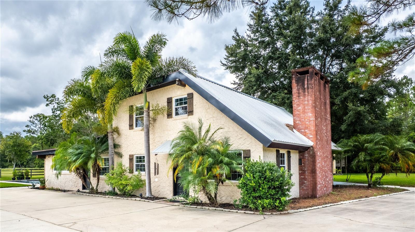 LOCATION, LOCATION!!! This charming country estate is situated on 5.20 acres of cleared, mowed, and fenced land and includes its own fish-stocked pond. Simply picturesque! This private countryside retreat is just minutes away from the Port Orange Pavilion, shopping, schools, I-95, I-4, and both Daytona and New Smyrna Beaches. The primary residence is full of character with wood tongue and groove ceilings with support beams throughout. The flooring is ceramic tile downstairs and wood plank upstairs. Enter the main home into an open concept Living and Dining Room combination, anchored with a large wood-burning Fireplace with a solid Wooden Mantle and Brick Hearth. The Valuted Ceilings are impressive, and the custom Iron Railing on the open second-floor catwalk staircase is beautiful! The Kitchen is large with abundant cabinet space. There are newer Stainless Steel Appliances for the cook in the family to utilize. The Office/Den/Sitting Room/additional Dining/ Room is a flexible space for the owner to define their needs. Step into the open and large Great Room filled with natural light that has a Summer Kitchen including an indoor grill, double sink, and bar. The French Doors open onto the Paver Patio and Pool Deck with the stunning newer Saltwater Pool. The pool has luxurious additional features of a Waterfall Fountain, Bubblers, Bench Seating, Pool Lighting, and Bench Stairs for entry and stacked seating. This area is an entertaining delight! On the first floor, the Primary Bedroom is located with an adjacent Bathroom. The large Bath vanity has a designated make-up area. There is a walk-in tiled shower and a newer stool. Upstairs, the two secondary Bedrooms share a Jack and Jill bathroom. The estate has several additional Buildings. The DETACHED OVERSIZED TWO-CAR GARAGE has an "IN-LAW BEDROOM, BATHROOM SUITE, with an area for a small Kitchenette. Currently, it has a refrigerator. There is also a large BONUS ROOM with a HALF BATH. This room is being utilized as a game room with a Pool Bath; however could be the 5th bedroom, art studio, man cave, personal gym, etc. The BARN is divided by a concrete walkway, has multiple stalls, and two tack rooms. The property also has a tall-ceilinged POLE BARN that is partially sided with a 1/2 concrete floor, perfect for parking many vehicles, boats, large equipment, etc. This structure has water and a 30-amp RV hookup. The SHED also has electricity for convenience. Zoned A-2, this well-maintained estate is both beautiful and versatile to meet your dreams. Sellers are offering a one-year Old Republic Home Protection warranty plan with an accepted buyer contract. Contact me to learn more and schedule your tour. Let's work together!