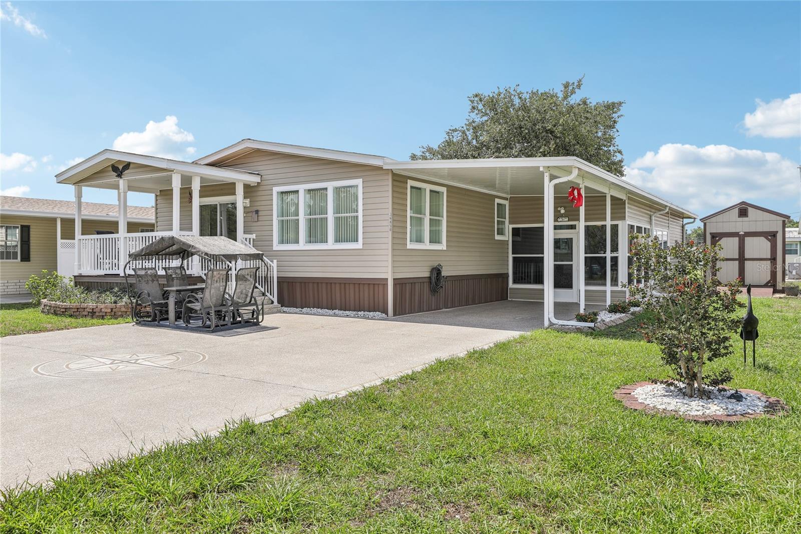 IMMEDIATELY AVAILABLE! This 2017 manufactured home offers 2 bedrooms, 2 bathrooms, plus a bonus room, perfectly situated just across from the community amenities. Upon arrival, you’ll be welcomed by a charming front rocker porch, an oversized side carport with space for two cars, and a screened porch with an attached storage/workshop area. Inside, the open floor plan seamlessly connects the kitchen, dining, and family room areas, with easy access to the front porch for enjoying morning coffee or evening breezes.
The home features two comfortable bedrooms, an oversized office/flex room that can easily serve as a third bedroom, and an interior laundry room for convenience. An exterior storage shed—currently used for golf cart storage—offers versatile space for hobbies or additional storage needs. The lot is nicely sized, providing room to enjoy the outdoors.
Located in the sought-after 55+ community of Betmar, this home offers more than just a place to live—it’s a lifestyle. Amenities include community buildings for events, three 9-hole golf courses, two swimming pools with therapeutic whirlpools, shuffleboard and bocce ball courts, a pavilion, gazebo, dog park, miniature golf course, and so much more. With clubs, events, and endless opportunities to stay active and social, Betmar is one of the most desirable communities for affordable, resort-style living.