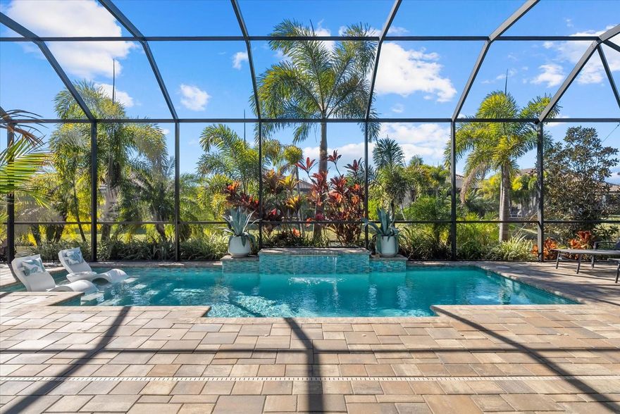 This is not your average builder home. A whole lot of upgrades and model-worthy finishes await you. From the moment you arrive, the expanded paver driveway, professional landscaping/lighting, and striking glass-insert front door signal that every detail of this Pallazio floor plan has been thoughtfully curated — and the interior delivers on that promise in every room.
Set within the sought-after, gated community of Esplanade at Artisan Lakes in the heart of Parrish's rapidly growing corridor, this home sits at an elevation of 33 feet — meaning no flood insurance required — on a generous, private .24-acre pie-shaped lot with tranquil pond views.  This street is also less frequented due to the cul-de-sac.
Step inside and you're greeted by designer lighting, marble tile accent walls, and custom mirrored dining space. The kitchen is loaded with storage and its extra large island is the centerpiece for entertaining. The main living area is equipped with professional 7.0 surround sound system, motorized shades flow seamlessly across the great room and kitchen, and ceiling fans and TVs are installed throughout — nothing was left as an afterthought.
The attention to detail continues throughout the home with an instant hot water system, reverse osmosis water filtration, and full cabinetry in the laundry room. The secondary bathroom has been recently upgraded well beyond standard finishes, and hurricane-impact glass windows and doors throughout provide peace of mind.  The primary suite and bathroom provides spacious relaxation along with views of the pool and palm trees.
Out back, the space is nothing short of a private retreat. A 625 sq. ft covered lanai extends your living space outdoors, where a heated saltwater pool with autofill system and a fully equipped outdoor kitchen await — all framed by peaceful pond views, lush tropical landscaping and the generous privacy that a pie-shaped lot affords. Whether you're entertaining or simply unwinding, this space was built for both.
Even the garage received the upgrade treatment — epoxy-coated floors, extended garage length, two overhead storage racks, and a 50-amp generator plug make it one of the most functional in the neighborhood.  A recent Wind Mitigation Report is also available, offering potential savings on homeowner's insurance.
Beyond the home itself, Esplanade delivers a true resort lifestyle with maintenance-free living, two amenity centers, three pools, eight pickleball courts, four tennis courts, and a vibrant social calendar. All of this in one of Florida's fastest-growing communities, with new hospitals, expanding dining and retail, and easy access to I-75, I-275, and US-41 — putting St. Petersburg, Tampa, Sarasota, and the Gulf Coast beaches well within reach.
Furniture and rugs available separately — potential turnkey opportunity.