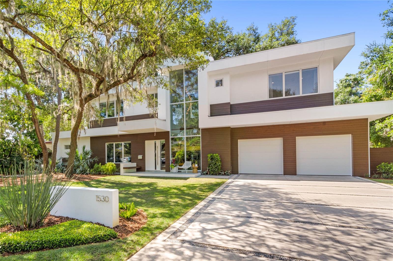 Located in Winter Park this home was devised by architectural firm, Green Apple & built by E2 Homes. Contemporary living adheres to a few principles that define its simple aesthetic: open-floor plan, clean lines, minimal clutter & a neutral color palette. This four bedroom, five bathroom almost 4,000 square foot, custom built pool home delivers on all of those principals & more. The bold, modern shell is composed of a warm, walnut toned wood, smooth finished white stucco & floor to ceiling large scale windows. It sits on a wide, expansive lot where low maintenance, organic style plant material was installed & where a breadth of other exterior materials were used such as zoysia, large square cement drive and walkways bordered by Alabama limestone chips that nicely compliment one another. The interior design continues to push the envelope & reimagine life within its walls. Through the custom front door your guests will arrive in the foyer where they will be greeted by an architecturally significant solid walnut, floating staircase & statement, pendant style light fixture both of which are showcased through the two story windows at the front of the home. To the left is a den or office that can be privatized by closing the double pocket doors. Moving forward the home opens to the living, dining, kitchen and outdoor spaces. The main area flooring is polished cement & that flooring continues to the covered outdoor space reinforcing the seamless connection between them. The kitchen was designed in collaboration with S&W where the cabinets were sourced. The Hanstone quartz countertops are Royale Blanc; a clear ivory that provides a harmonious ambience, unfettered by patterns or design. Masterpiece series, stainless steel Thermador appliances including a gas fueled cooktop with five burners, vent hood, double ovens, counter depth refrigerator/freezer & dishwasher. Two under counter, built-in wine refrigerators & microwave located in the hidden pantry are also included. The living & dining areas open via floor to ceiling, multi panel sliding glass doors to the deep, covered outdoor living space & Summer Kitchen. The Summer Kitchen features a professional DCS outdoor grill and sink with the smart design and functionality of a sliding glass pass through to the kitchen. The dreamy outdoor living has many of the interior comforts. The saltwater & heated pool, spa and natural gas fueled fire feature with seating area and composite deck for lounge chairs are almost entirely surrounded by mature bamboo for the ultimate privacy resulting in what feels like a backyard sanctuary. The primary bedroom suite, located on the first floor, has beautiful views of the lush backyard with motorized window treatments. The spa like bathroom features a vanity with quartz countertops, double sinks, a large stand alone bathtub, private water closet, spacious shower tiled with Calacatta Gold marble & multiple shower heads as well as a large closet customized for optimal storage. Upstairs you will find a loft & guest suite on the right side of the home & two bedroom suites on the left. The home is completed by an oversized & attached two car garage, parking pad, laundry room with significant storage, a hidden pantry with custom organization, Storch Entertainment A/V package with flat screen televisions mounted to the wall, sound bar, surround sound speakers, Apple TV for streaming content, etc. This luxury custom home is available for private showings now.