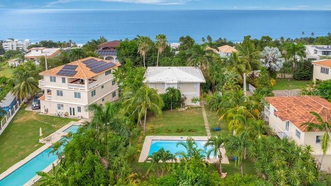 Located on one of the most sought after streets in the Puntas neighborhood of Rincon, this 2 unit property is less than 300 meters to world class surfing, beautiful beaches and the Sandy Beach area restaurants and activities. The main home is on the second floor, with a large covered balcony, 2 bedrooms (Primary suite has an en-suite bathroom) and a shared bathroom in the hallway plus open concept kitchen to living area with accordion style doors that open to the balcony with ocean views and breezes. The first floor is a 2 unit, 2 bath rental unit with full kitchen, large balcony and private access as well as garage access. The landscaped yard is just over 1,000 Square meters with room for another structure and features a large in ground swimming pool and fencing on the perimeter. This is a fantastic live-in and rent the 2nd unit or rent both, there are no restrictions. This is one of the most reasonably priced properties on this street where many the homes are valued over 2 million dollars