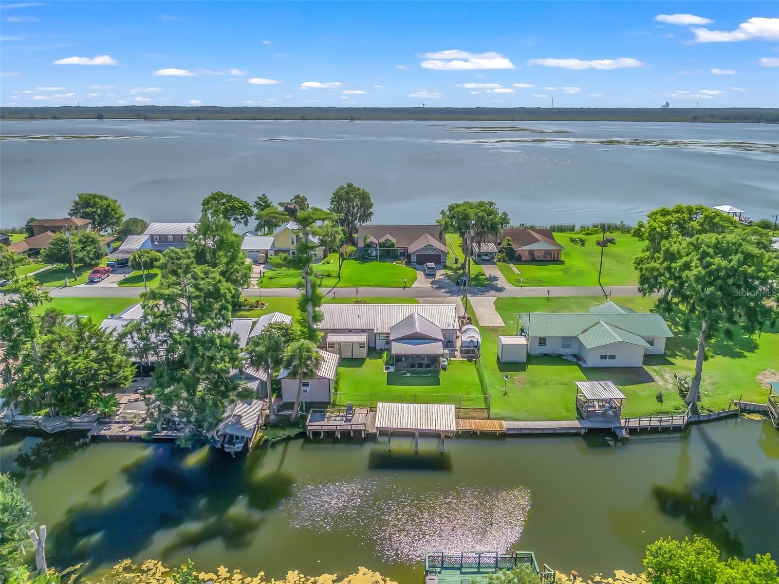Welcome to your ideal Florida retreat, perfectly positioned on a peaceful canal just 700 feet by boat to the open waters of Lake Panasoffkee. This beautifully updated 3-bedroom, 2-bathroom home blends relaxed indoor living with exceptional outdoor amenities in a serene, waterfront setting. Step inside and discover a light-filled interior where style meets function. The kitchen is a standout feature, offering glistening granite countertops, a sleek tile backsplash, ample cabinet space, and a picture-perfect canal view right from the sink—making everyday living and entertaining a true delight. Both bathrooms have been tastefully renovated with a contemporary touch and include custom tile walk-in showers, upgraded vanities, solid surface top, and modern fixtures. Clean lines and elegant finishes are consistent throughout this lovely property. The home offers vinyl flooring throughout—easy to maintain and ideal for Florida living. A versatile flex room provides a stunning view of the water, making it a perfect spot for a home office, hobby space, or additional lounging area. Step outside to the screened back porch and enjoy peaceful mornings or evening breezes overlooking your private backyard oasis. For those who love to fish or boat, the outdoor features truly shine. Enjoy your 19x10 private fishing dock complete with a convenient fish cleaning station and a 24x10 covered boat lift rated for up to 6,000 pounds. Additional bonuses include a durable metal roof, energy-efficient tankless water heater, fenced backyard, a dedicated workshop, and a separate shed for all your storage needs. A true bonus is the whole house Generac generator, offering great peace of mind with automatic transfer of power, plus the fuel tank is on site and owned, not leased. Whether you're searching for a full-time residence or a relaxing weekend escape, this home delivers the very best of lakeside living—thoughtfully updated and move-in ready. Schedule your private tour today and discover what makes this waterfront gem so special!