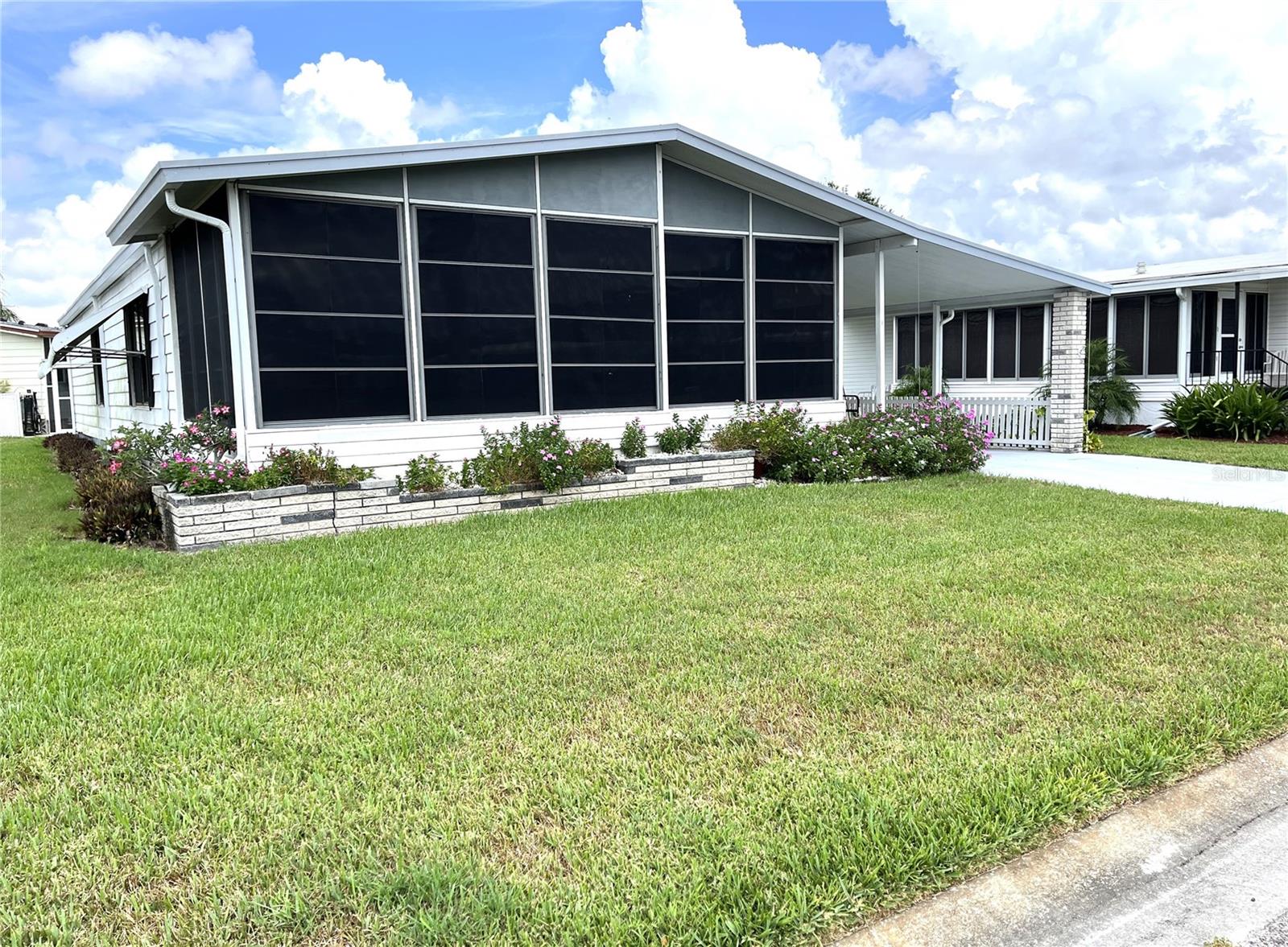 Nice 2 bedroom, 2 bath home in the popular 55+ community of Harbor Isles. Own your land, bring your pets and enjoy the myriad of activities and amenities year round. The marina is first come, first serve with docks, boat launch, kayak/canoe launch, fishing station and pavilion. Lovely elevated front porch is enclosed and great for people watching while enjoying your morning coffee or afternoon libation! Large galley kitchen is light & bright with plenty of counter space and storage. The living room is spacious and open to the dining room, both with plantation shutters. The primary en-suite will accommodate a king size bed and has a good size closet. Bedroom 2 is conveniently located just steps away from the guest bathroom. There is a screened lanai in the carport with direct access to the exterior utility room. This home is ready to go and is ready for a new owner and their personal touches. Walking distance to the recreation area. Convenient to shopping, dining, entertainment, Braves ball field, downtown Wellen Park, beaches, interstate, airports and more. Call today for your personal tour!