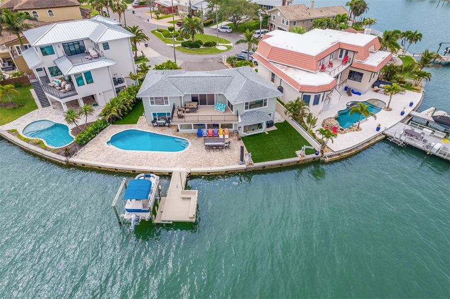 TUCKED AWAY IN THE HEART OF REDINGTON BEACH AND SURROUNDED BY HIGH-END, MULTI-MILLION DOLLAR HOMES THIS WATERFRONT PROPERTY IS THE EPITOME OF LUXURY AND COASTAL LIVING.  This astonishing 4 bedroom, 4 bath, 2 car garage home with nearly 4,000 HEATED SQFT is happily nestled on 113 feet of seawall overlooking the breathtaking views of Boca Ciega Bay from sunrise to sunset. SAIL BOATS WELCOME! Step foot under the arched patio and through the custom solid oak double front doorway to be greeted by 20+ foot ceilings in the grand tiled entryway.  From this point forward you will find the living area is bright, boasts natural light and is open to the dining room and kitchen making it ideal for entertaining while enjoying the panoramic water views from every angle.  Completely renovated in 2018, the gourmet chef’s kitchen exhibits dazzling quartz countertops, coveted 10 ft oversized island, stainless steel LG appliances, built-in icemaker, a brilliant composite granite double sink, custom backsplash and an excess of cabinets and storage space.  While still in the west wing of the main level you will find the downstairs laundry room and full guest bath also renovated in 2018 with tile floors, quartz countertops and glass shower enclosure.  Over in the east wing of the main level you will find 2 bedrooms separated by their own updated full bathroom with dual sink vanity, quartz countertops and gorgeous tiled shower with glass enclosure.  One of the bedrooms is currently being taken full advantage of as an office with views that are to die for.  Make your way up the contemporary floating staircase and be pleasantly surprised with not only one but two split floor plan owner suites divided by a bonus space / rec room with three sliding glass pocket doors overlooking 448 SQFT Trex deck balcony.  East wing master suite elegantly entails unanticipated multi-directional views of the sunlight gleaming over the bay's sensational waterway.  It features its own en-suite bathroom with quartz countertops, dual head rain shower and coastal themed colors.  Last to mention inside the home but far from the least is the 700 SQFT owner’s suite on the West wing worth bragging about.  The en-suite bathroom offers vanities on either side with an excess of sparkling quartz countertops, cabinet space, private water closet, custom tiled walk-in shower with glass enclosure and doors leading you to both the two separate walk-in closets and into the bedroom.  The 400 SQFT bedroom itself has plantation shutters on one wall and remote control shutters on the other two.  The uninterrupted views will not go unnoticed as this suite has it’s own private glass sliders to the balcony which lead us to take a look back down at the backyard, the true show stopper.  The water views are one thing from inside this home but an entirely different story once you get outside.  Step foot on to the travertine tile and you’ll be in awe as the approx. 30,000 gallon pool implores you to take a dip with a new polaris pump and filter.  On either side of the travertine you will find maintenance-free and pet-friendly artificial turf that was installed in 2019.  Sitting pretty right in the middle of the 113 ft of seawall (2016 seawall cap) there is the 2016 Trex dock with newer 2020 10,000 LB boat lift.  This immaculate home is sure to check all of the boxes of waterfront living in paradise.  Buyer to verify all measurements.