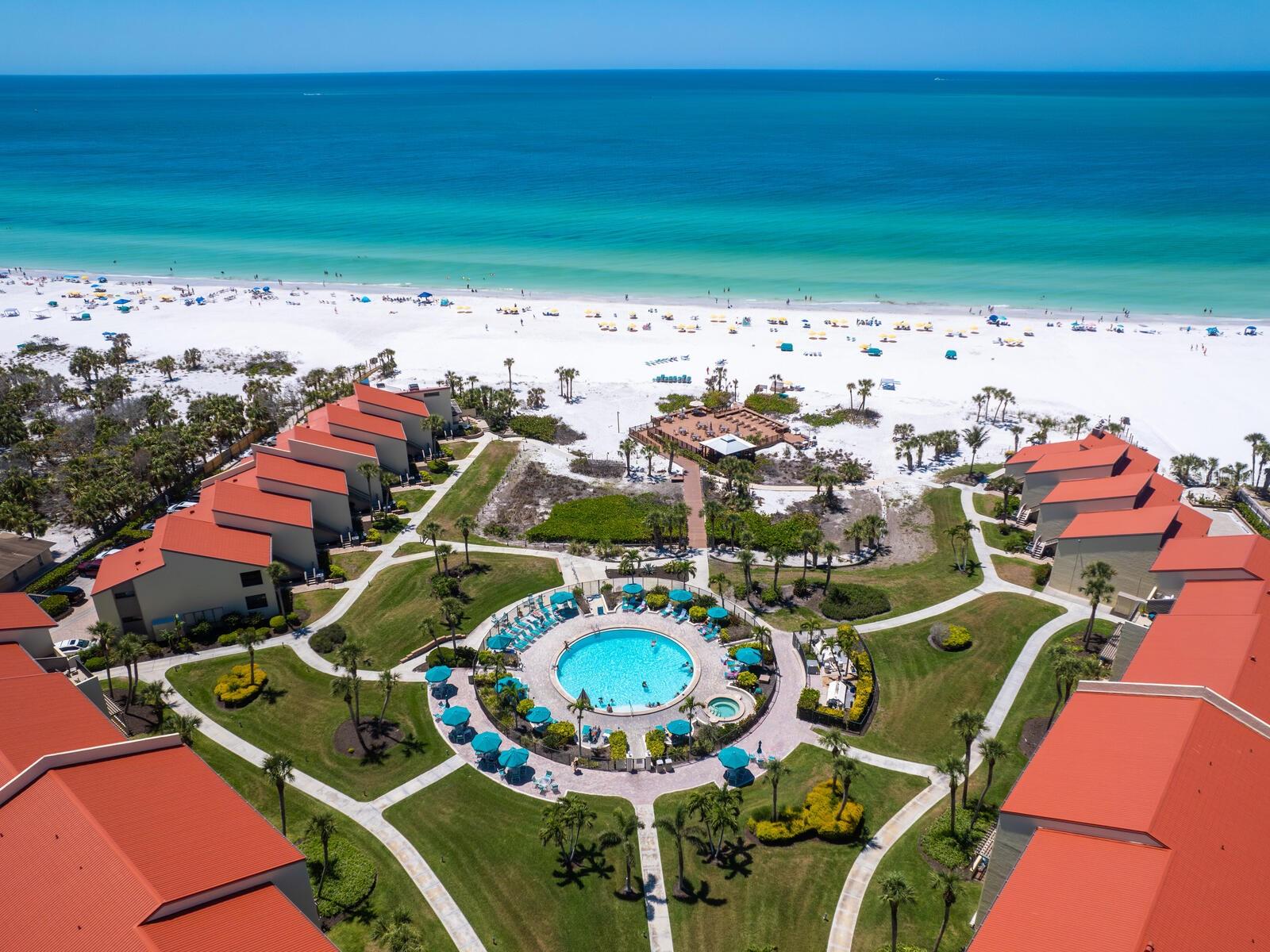 Welcome to your slice of paradise in the sought-after beachfront community of Siesta Dunes on Siesta Key! This first-floor turnkey furnished condo(with just five steps to the front door) provides easy access while remaining elevated for peace of mind during heavy rains. Inside, you'll find tile flooring throughout the main living areas and carpet in the bedrooms, creating a warm, inviting feel. Step into a light and airy living space that opens to a glass enclosed lanai with screens, ideal for catching the coastal breezes. Enjoy tranquil views of a lush, park-like grassy area-...your own peaceful retreat. Off the Primary bedroom, a charming outdoor patio with a trellis pergola invites morning coffee or evening wine under the stars. The split-bedroom floor plan offers privacy for both owners and guests, with each bedroom featuring a walk-in closet. The open-concept kitchen is both stylish and functional, featuring unique recycled glass countertops, stainless steel appliances, a cheerful light turquoise subway tile backsplash, and a large open breakfast bar perfect for casual dining and entertaining. A full-size stacking washer/dryer are nearby adjacent to a pantry closet for extra storage. The condo includes your own carport conveniently located right outside your front door, along with a spacious 4'X9' storage closet for all your beach toys and gear. Community grills are close by. A large round saltwater pool is just steps from the beach, plus an elevated sun deck/pavilion perfect for lounging, grilling, and watching breathtaking sunsets, a cherished tradition at Siesta Dunes. The on-site tennis court is easily convertible for pickleball, making it perfect for fans of both sports. This gated community is meticulously maintained, well managed, offering excellent rental flexibility with 2-week minimums from January 15 through April, and 1-week minimums the rest of the year. Whether you're looking for your own piece of paradise or a property with strong rental income potential, this Siesta Dunes condo has it all.