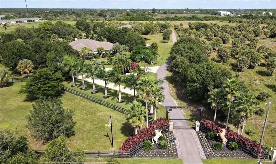 Experience the perfect blend of peaceful country living and everyday convenience at Tall Palms Ranch in Rowland Country Estates. Ideally located just 10 minutes from Charlotte Harbor and historic downtown Punta Gorda, this private gated sanctuary offers over four beautifully maintained acres with room for horses and livestock — all while remaining close to shopping, dining, schools, and waterfront recreation.
Enter through the private gate and follow the stamped concrete circular drive to this custom-built 5-bedroom, 2.5-bath estate home offering 3,645 square feet of thoughtfully designed living space. Lush tropical and mature landscaping surround the property, creating exceptional privacy and a serene natural setting.
Inside, the open floor plan is anchored by a striking stone wood-burning fireplace in the great room. The spacious kitchen is designed for both everyday living and entertaining, featuring solid wood cabinetry, solid surface countertops, stainless steel appliances, cooktop, built-in microwave and oven, breakfast bar, and an expansive walk-in Butler’s pantry.
The generous primary suite is a private retreat with an impressive 12’ x 14’ walk-in closet and a spa-like ensuite bath complete with dual vanities, jetted tub, and walk-in Roman shower. Three additional bedrooms provide ample guest space, with one currently serving as a home office.
Step outside to your own backyard oasis. The covered lanai, tiki bar, and 26’ x 58’ screened pool area with rock waterfall create the ultimate setting for entertaining or relaxing. Enjoy peaceful views of the private pond and abundant wildlife from the gazebo or unwind on the cozy front porch as you take in the tranquil surroundings.
Additional features include 20’ x 20’ garage/storage shed, 500-gallon buried propane tank for whole-home generator and Zoned Agricultural for multiple use options.
Just minutes from the boating and fishing waters of Charlotte Harbor and the vibrant charm of downtown Punta Gorda, known for its arts scene, community events, and waterfront lifestyle, this exceptional property offers the best of Florida country living with modern comfort and convenience.
Adjacent commercial property and 24 acres of contiguous vacant land are available for sale separately including A CAR LOVERS DELIGHT- a versatile building featuring 900 sf air-conditioned hobby shop and 5,400-sf garage/workshop with 8 overhead doors including 3 tall doors to accommodate RV’s. The shop features a 9,000 lb. auto lift and plenty of space to store and work on boats, trucks, classic cars and farm equipment plus there is 900 sf of office space for a total of 7,200 sf. 
Don’t miss this rare opportunity to own your private Florida ranch retreat in the heart of Port Charlotte.
