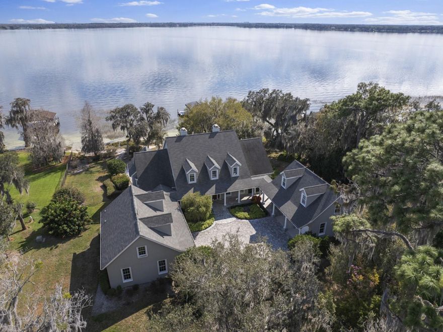 OVER 1.7 ACRES OF LAND ON LAKE BUTLER AND MORE THAN 230 FEET OF WATER FRONTAGE! Located on one of the most desirable streets in beautiful downtown Windermere, this custom-built home is positioned on over 1.7 acres with an amazing, wide open view of famed Lake Butler. As you enter the winding drive, you will arrive at this stunning residence created by renowned custom home builder Akers Construction. A sprawling front porch summons you home as you step into the interior space that is filled with top-of-the-line interiors and finishes. No detail has been overlooked. Unique architectural highlights include arched and paneled entryways and large windows that provide abundant natural light throughout the home. The open kitchen features tile floors, a large island, and additional counter space, ideal for sitting and sharing early morning meals. The family room offers a comfortable layout with beamed ceiling detail, as well as beautiful lake views from the window seat. The huge dining room is ideal for entertaining and sharing memorable holiday meals among friends and family.  A nicely appointed formal living room with lake views and a large fireplace is designed for comfort and entertaining. The large home office is private and perfect for quiet pursuits. The primary bedroom suite on the first floor is spacious and offers a private sitting area with lovely lake views. The primary bath boasts his and her vanities, marble details, a walk-in shower, a soaking tub, and a lovely stained-glass window. There is an additional room off the primary bedroom hall that would be ideal for a gym, nursery, additional closet space or more. Upstairs, three ensuite bedrooms are expansive, each with a large closet and beautifully designed bathroom. Two over-sized garages offer parking for four cars as well as depth and height for additional storage. Above the west garage you will find a fully equipped guest apartment with living /dining area, kitchenette, bedroom, and full bath. The ground level of this garage has a workshop area and a steel beam with hoist for use with heavy equipment. The east garage features an unfinished second floor, useful for additional living space or insulated storage. On the lower level of the home, adjacent to the pool, you will find a large recreation room for entertaining and a pool bath. Outside, the sparkling pool includes a spa and cascading waterfall. The pool is also accessible by a sweeping stairway leading down from the screen porch and upper patio off the living room and family room. And what will surely be your favorite place to spend sunsets is the more than 230 feet of pristine water frontage and private white sand beach, inviting you to experience the true wonder of Florida living. The home also features one of the largest, private boat docks on the Butler chain with three covered boat lifts, perfect for a boat enthusiast. The dock roof supports solar panels that partially power the home. Another bonus of this home is the large under-house storage area for boating and outdoor equipment. Schedule your tour of this breathtaking property today! NOTE - PRICE INCLUDES ALL THREE ADJOINING PARECELS WHICH EQUATE TO 1.72 ACRES.