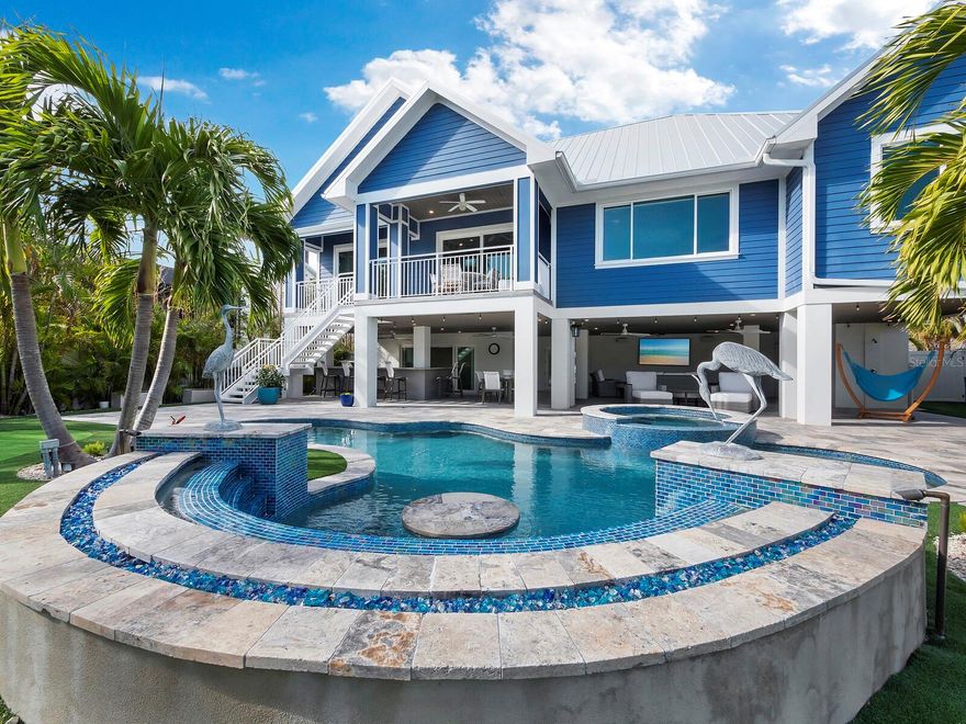 Here is your opportunity to own one of the nicest (and newest) homes in the highly sought after "Village" of Longboat Key. A tranquil escape all done up in seaside hues, new in 2022, and then upgraded even further by the current owners. This ELEVATED home is a paradise unto itself! An entertainers dream, it features a fabulous chef's kitchen with a natural gas range, double ovens, high end appliances and a large island that is open to the designer furnished dining area and great room. All of the fabulous furnishings and art convey - it is being offered TURNKEY furnished. Light fills the entire home through impact rated windows and sliding glass doors. Open the sliders to an outdoor covered patio and enjoy the incredible view of the one of a kind backyard oasis. Steps lead down to the gorgeous pool and spa with a fire feature surrounding the in-the-pool seating. Adding to the remarkable backyard is a large covered outdoor kitchen and bar, a covered dining space and seating area with a big screen TV. There is even a putting green!! A 3 car garage makes room for all your toys. Just a short distance away is the gorgeous Broadway beach that stretches all the way around to Greer island. The “Village” has its own community dock and boat ramp so enjoying your days on the water are easy. When you return, there are a number of restaurants ranging from fine dining to casual eateries right here in your neighborhood. Luxury island living doesn’t get much better. Come see this amazing home today and envision living the laid-back luxury island lifestyle that Longboat Key is known for.