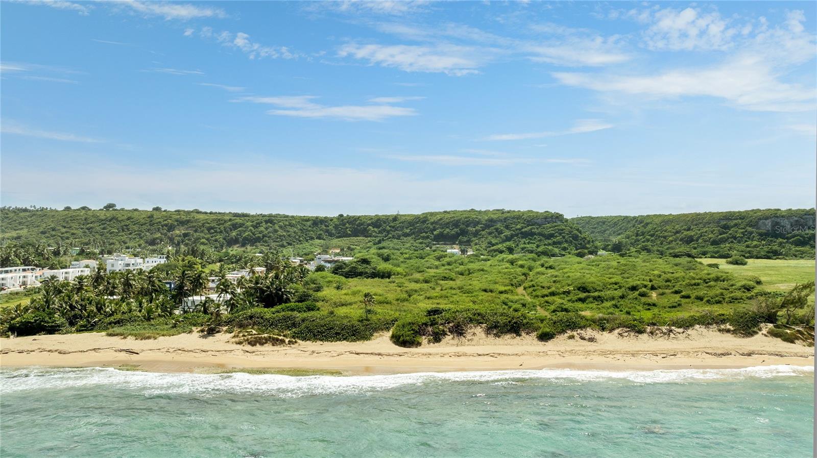 Introducing an unmatched slice of paradise with approximately 7 acres of rare beachfront lot opportunity. Perfectly poised to offer breathtaking Atlantic Ocean views and endless development potential in Puerto Rico's highly sought-after west coast town of Isabela. With 95 linear meters of prime beachfront, this lot provides direct access to 5 miles of uninterrupted sandy shores that connect to 13 stunning beaches, including the renowned Jobos, Montones, Poza Teodoro, Pozo de Jacinto, Shacks, Golondrinas, and Bajuras Beach. This opportunity includes all the necessary permits for a residential-tourism project, offering a streamlined path to development.
Conveniently located just a short 10-minute drive from Rafael Hernández Airport (BQN), the second-busiest airport in Puerto Rico, this property offers direct flights to major cities such as New York, Newark, Fort Lauderdale, and Orlando. Isabela is known for its rich culture, historical landmarks, and iconic beaches, which are perfect for water sports, including surfing, snorkeling, diving, and marine fishing.
Celebrated as the 'Capital of Surfing' in the Caribbean, Isabela hosts prestigious championships that attract surfers from around the globe. The coastal town also features the scenic Paseo Lineal de Isabela for cycling and jogging, along with the acclaimed Links at Royal Isabela. Golf enthusiasts can enjoy breathtaking ocean vistas and a naturally designed golf course perched 200 feet above the ocean, as featured in Golf Digest magazine. Nestled near the picturesque towns of Rincón, Aguada, and Aguadilla, Isabela captures the true spirit of Caribbean living, presenting an exceptional investment opportunity.