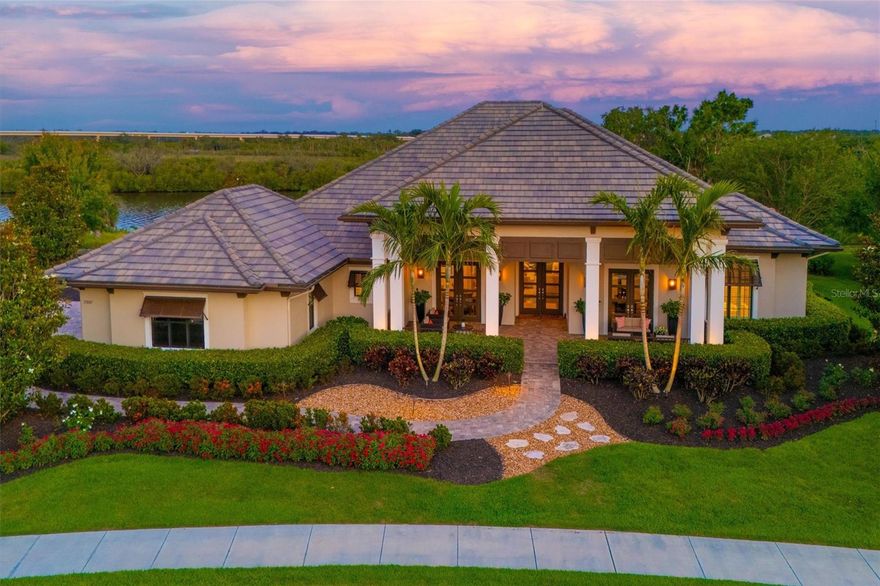 Florida waterfront living at its absolute finest. Nestled directly on the Manatee River inside the private, gated community of The Islands on the Manatee River, this exceptional estate offers rare privacy, breathtaking views, and true resort-style living. From the moment you arrive, the home impresses with lush, manicured landscaping and a grand covered front porch featuring two welcoming sitting areas. Inside, the open-concept design is highlighted by soaring 25-foot vaulted ceilings and dramatic floor-to-ceiling pocket sliding doors that seamlessly connect indoor and outdoor living. The home offers three spacious bedrooms plus a bonus room complete with a wet bar and mini refrigerator—perfect for entertaining. The chef’s kitchen is a showpiece, outfitted with premium appliances including a GE Profile Sub-Zero refrigerator and freezer, along with Wolf range, oven, and microwave. The expansive primary suite is a private retreat, featuring a sitting area, dual custom walk-in closets, and a spa-inspired bathroom with a soaking tub and an oversized walk-through shower with dual entrances, three shower heads, and a built-in bench. Step outside to your own resort oasis overlooking the river and protected natural preserve. Enjoy the heated pool with tanning ledge, relaxing hot tub, and covered patio with roll-down screens ideal for outdoor dining and lounging. Brand new pool/spa pump and filter just installed! A private walkway leads to your dock with a brand-new (Q1 2025) 20,000-lb boat lift, capable of accommodating virtually any vessel—perfect for boating enthusiasts. Additional highlights include a three-car side-load garage with custom cabinetry, a new AC system (2024), and a prime location offering easy access to Sarasota, Lakewood Ranch, St. Petersburg, and Tampa. This is a rare opportunity to own a luxurious riverfront retreat that truly has it all.