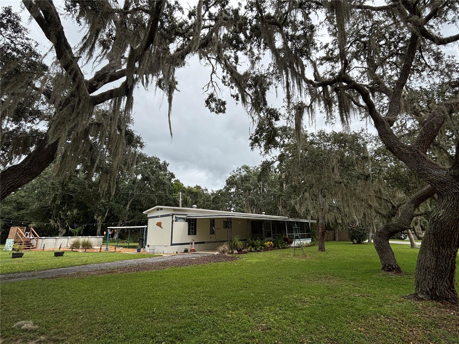 Come see this 2/2 Singlewide Pool home on a massive .52 acre corner lot (three total lots)! Enjoy the picturesque trees in the front yard with gorgeous Halfmoon Lake view sunsets across the street right from your front porch! Cool off in the newer built 12 x 24 x 5 oval above-ground pool with a wood deck stairway, along with a concrete walkway and a beautiful decorative rock garden surrounding the pool entrance area. Convenient 20 x 10 covered patio/grilling area perfect for pool parties. Paved street leading to a paved driveway to an attached 29 x 14 two-car carport. Big attached 20 x 14 screened-in porch on a slab, 10 x 10 outside laundry room with workshop and a massive 22 x 10 storage shed. Small fenced area in the backyard for a small dog and also a privacy fence on the backside of the property along with hurricane shutters. Inside features a complete brand-new kitchen with new countertops, cabinets, kitchen island and additional shelving/cabinets all in 2024! New vinyl flooring in the kitchen and living room along with paint and ceiling fan are also new in 2024. Spacious master bedroom with his and her sinks in the master bathroom. Bay windows in guest bedroom along with a full bath. Home is located in the Ocala National Forest which affords you almost a ½ million acres of Forest to roam, 600 lakes, 2 rivers, Juniper Springs, Silver Glen Springs, Salt Springs, Swimming, Skiing, Big BASS Fishing, Boating, Camping, Hiking, Horse back riding and some of the best ATV riding anywhere. Daytona Beach is just 1 hour away. The seller will leave the riding lawnmower, make this home yours today!