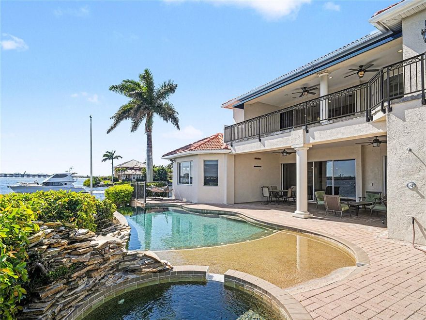 Welcome to an exceptional waterfront estate, gracefully positioned at the end of a palm-lined cul-de-sac on a private peninsula within the exclusive gated community of Riviera Dunes. Set along the peaceful Manatee River, this residence captures breathtaking sunset views and offers a refined coastal lifestyle with convenient access to the Gulf of Mexico via the community’s deep-water marina. This furnished custom home spans over 4,400 square feet of elegant living space and more than 5,700 total square feet designed for both luxurious everyday living and grand-scale entertaining. From the moment you arrive, the paver driveway, striking curb appeal, and three-car tandem garage with designer checkerboard flooring set the tone.  Inside, expansive tray ceilings with ambient lighting, custom ironwork, and timeless finishes create an elevated  yet inviting atmosphere. A grand formal dining room is perfect for hosting, while the massive great room, anchored by a gas fireplace and custom built-ins, offers both comfort and style. The gourmet kitchen is thoughtfully appointed with granite countertops, natural wood custom cabinetry, a walk-in pantry, built-in desk, wet bar, and premium appliances including Thermador and Sub-Zero. The main-level owner’s suite is a private sanctuary, featuring serene water views from every window, a custom walk-in closet, and a spa-inspired bath with glass shower, dual vanities, abundant storage, private commode with bidet, and an in-suite wet bar. Upstairs, a spacious family and recreation area with kitchenette opens to an expansive balcony overlooking the water, ideal for relaxing or entertaining. Step outside to your private waterfront retreat, where a covered patio and seating area lead to a stunning beach-entry, heated, saltwater, infinity pool, perfectly positioned to take in spectacular sunset views over the river. Built for both beauty and peace of mind, the home features hurricane impact glass, a concrete seawall, and has experienced no flooding during recent storm events, an exceptional benefit for waterfront living. Additional highlights include a wine cellar, tile flooring throughout, stucco exterior, and a classic barrel tile roof. While this property does not include a private dock, Riviera Dunes offers one of Southwest Florida’s safest deep-water harbors, with boat slips often available for purchase separately, providing convenient boating access to the Gulf in approximately 10 minutes. This home is ideally located just minutes to I-75, approximately 45 minutes to Tampa International Airport, 30 minutes to Sarasota-Bradenton International Airport, and close to premier shopping and dining at Ellenton Premium Outlets and University Town Center. This is more than a home, it’s a rare opportunity to experience waterfront living with unmatched sunsets, elegance, and privacy.