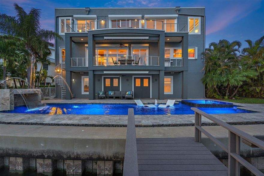 Discover the pinnacle of coastal luxury living with this exceptional custom contemporary 3-story waterfront residence on the coveted Boca Ciega Bay poised at the end of cul-de-sac. This immaculate green home with 16MWp of solar generation, is a harmonious blend of contemporary architectural elegance, modern convenience, and provides a view of unparalleled natural beauty. Boasting 4 spacious bedrooms, 4 well-appointed baths, an amazing chilled and heated pool with spa, a dock with 2 lifts (25,000 and 15,000 pounds), this residence offers a sanctuary of comfort and opulence for both owners and guests. Each room provides an ambiance of refined sophistication and breathtaking water views. Upon entering, you'll be captivated by the amazing water views and grandeur that unfolds before you in the spacious wide open floor plan. The gourmet kitchen, an epicurean haven featuring an abundance of counter space, custom cabinetry, new Wolf double oven, new Bosch dishwashers, new cooktop and an inviting island that effortlessly transitions between casual family meals and lavish entertaining. The allure of the outdoors is seamlessly integrated through the wall of sliding glass doors, which frame breathtaking vistas of the Boca Ciega Bay. The home features a primary suite on the third floor, a bonus loft area that serves as a second living room and 2 additional bedrooms. Outdoor entertaining becomes a breeze with an elevator, offering a seamless fusion of indoor and outdoor living. The first-floor great room could also serve as an oversized in-law suite or Nanny quarters. Whether hosting an intimate gathering or a grand soirée, this home is a testament to luxury and leisure, where culinary delights are prepared and served against the backdrop of shimmering waters. Enjoy smart home features such as voice command lighting, blinds, garage door, AC and indoor/outdoor Sonos Sound System. From its prestigious location at the end of a cul-de-sac to its panoramic vistas, this home is a tribute to refined coastal living, where luxury, comfort, and natural beauty unite in perfect harmony. The home is a short walk or golf cart ride away to the Redington Beach Resident-Only Parking Area with beach access and John's Pass is a quick boat ride away.