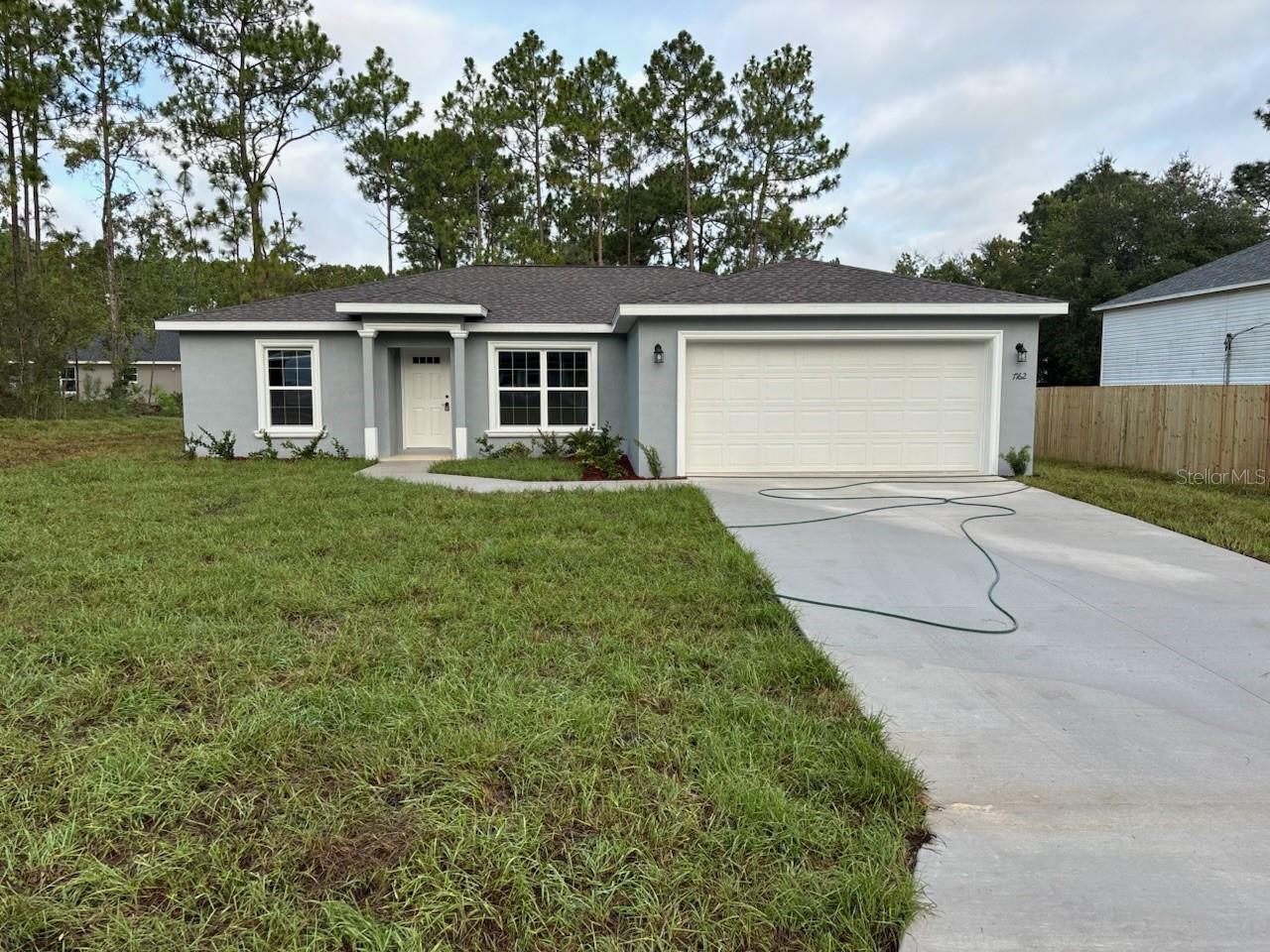 NEW CONSTRUCTION. MOVE-IN READY! This beautifully designed Key West model in Dunnellon offers 3 bedrooms, 2 bathrooms, and 1,405 square feet of thoughtfully planned living space. Built with solid concrete block construction and topped with a 30-year architectural shingle roof, this home combines lasting quality with everyday comfort. The vaulted ceiling in the living room adds a sense of spaciousness, while energy-efficient double-pane windows bring in natural light. The home features the builder’s LARGEST MASTER SUITE, complete with a glass-enclosed shower and upgraded marble-look tile in the bathroom. Throughout the home, luxury vinyl plank flooring offers both style and durability. The kitchen includes granite countertops, custom white shaker cabinets with soft-close drawers, a subway tile backsplash, a large pantry, and stainless steel appliances. Additional highlights include a laundry room with upper cabinets, granite in both bathrooms, a tub/shower combo in the main bath, and a privacy fence along the right side of the yard. Relax outdoors on the covered patio or pull into the attached 2-car garage, which includes an opener and remotes. With no HOA fees and a location in flood zone X—high and dry with no flood insurance required—this home offers both peace of mind and freedom.
