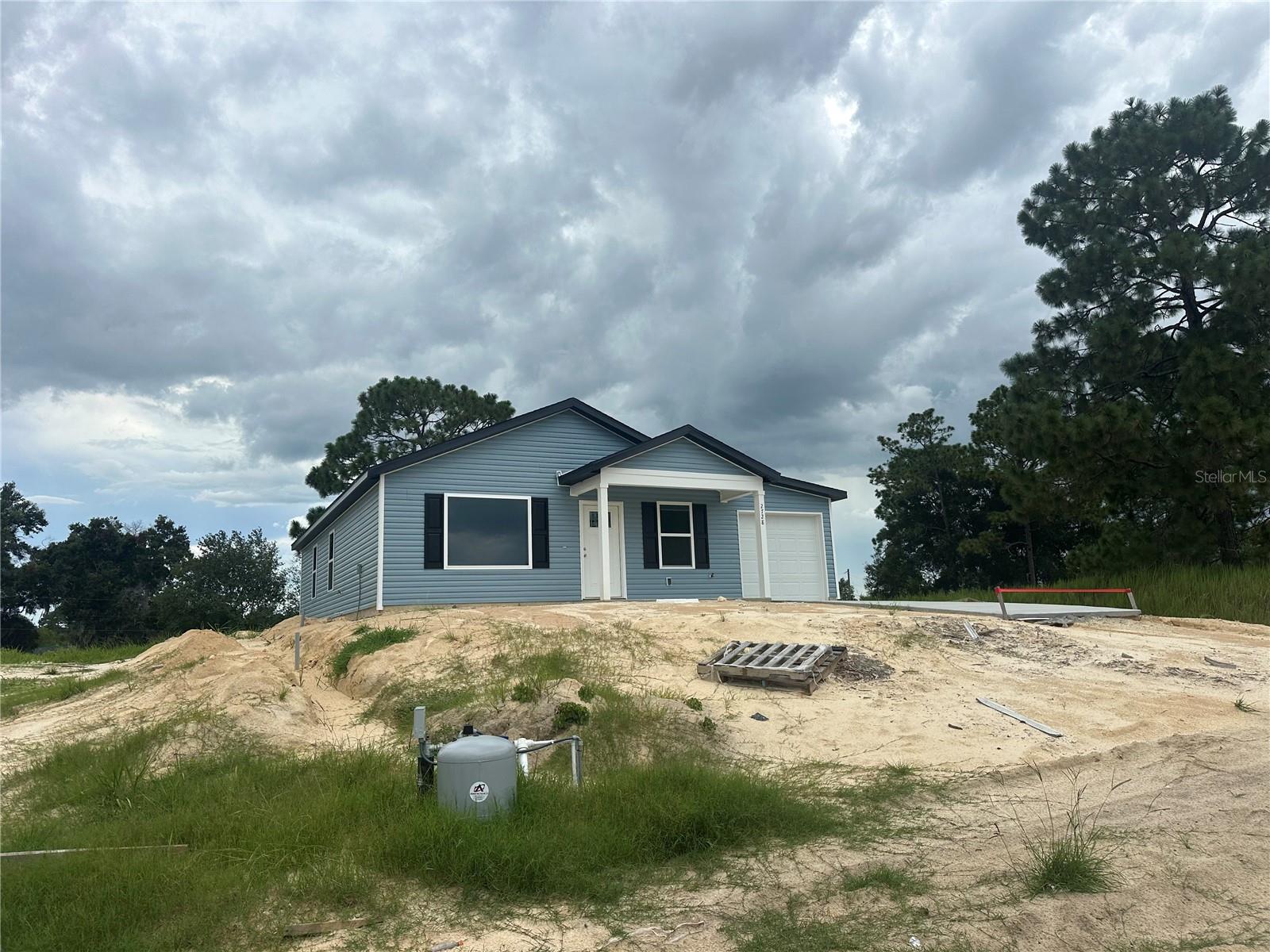 Under Construction. Welcome to this exciting new construction project, a charming and affordable cottage home in the desirable Rainbow Park neighborhood, just a quick drive to the scenic Rainbow River. This home offers an excellent opportunity to experience comfortable living with its well-designed features. Key Features: Spacious Rooms: Enjoy the luxury of generously sized rooms, providing plenty of space for relaxation and everyday activities. Open Kitchen: The home features an open kitchen layout, creating a seamless flow between the kitchen and living areas, perfect for entertaining and family gatherings. Elegant Kitchen Upgrades: The kitchen will showcase granite countertops, adding a touch of elegance to your culinary space. Stainless steel appliances provide modern convenience and functionality. Stylish Flooring: The choice of vinyl plank flooring enhances the home's aesthetic appeal while offering easy maintenance and durability. Country Porch: Picture yourself unwinding on the charming country porch located at the front of the home. It's an ideal spot to enjoy the neighborhood atmosphere and relax outdoors. Unique Roof Design: This home stands out with its 6' 12" pitch roof, adding character and curb appeal, making it one of the most adorable houses in the neighborhood. Three Bedrooms, Two Bathrooms: With three bedrooms and two bathrooms, this home offers a comfortable living space, providing ample room for residents and guests. 1-Car Garage: The inclusion of a 1-car garage provides convenient parking for your vehicle and additional storage space. Cleared Land: The property's land is already cleared, laying the foundation for a smooth and timely construction process. Please note that the home is currently under construction. While pictures and virtual tours are available to offer an accurate depiction of the completed home, there might be slight variations in interior colors. Given its appealing features and prime location near Lake Weir, this home is expected to sell quickly. Don't miss out on the opportunity to own a lovely cottage home in Rainbow Park—an alternative to tiny home living without compromising on the number of bedrooms. Color will be Blue.