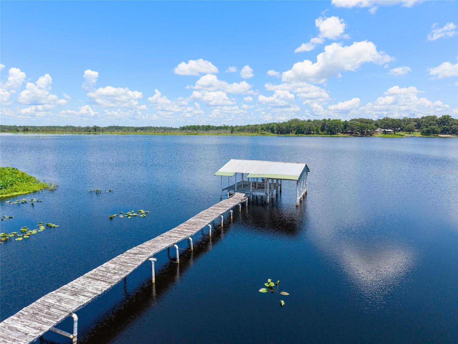 Lakefront Pool Home on 2+ Acres – Your Private Retreat Awaits at a great new price! Escape the hustle and find your slice of paradise with this beautifully maintained lakefront POOL home on the serene shores of Little Orange Lake. Situated on 2.11 landscaped acres, this 3-bedroom, 2-bath home combines peaceful rural living with stunning water views and exceptional amenities. Enjoy panoramic lake views from nearly every room, thanks to newly upgraded lakeside windows (with a transferable lifetime warranty). The open-concept layout is designed to take full advantage of the scenery, with a spacious living area featuring a tongue-and-groove vaulted ceiling and a gas fireplace in the dining space. The kitchen is a chef’s dream—complete with granite countertops, stainless steel appliances, generous cabinetry, and pull-out pantry storage. The primary suite is a true retreat, offering lake views, an updated bathroom with double sinks, a walk-in shower, and a large closet with dual access. Two additional guest bedrooms and a full bath with a jetted tub round out the main home. Step outside to your private oasis: a screened saltwater pool with power and pad for a hot tub, grilling area, oversized lanai, and fenced backyard—all overlooking the lake. The property includes a 2-car attached garage with overhead storage, a detached 20' x 14' pull-through garage/workshop with loft, and a separate guest or in-law cabin with its own bathroom (bathroom 3), kitchenette, and porch. There's also an additional 12' x 24' detached cabin ready to finish as a studio, office, or guest space. Additionally, a lean-to/carport offers more space to store your toys or mower. Boaters and gardeners alike will love the two docks (one fixed, one floating), boathouse, fruit trees, and herb and flower gardens. The home can be sold turnkey—including a pontoon boat and John Deere mower and has great potential for a short-term rental. Little Orange Lake spans 576 acres and is perfect for boating and fishing, with a public boat ramp nearby. Neighboring land owned by the Putnam Land Conservancy provides added peace and privacy. Roof (2018) and water heater (2017) already updated. Don’t miss this rare opportunity to own a fully equipped lakefront retreat with space, charm, and incredible extras—schedule your showing today!