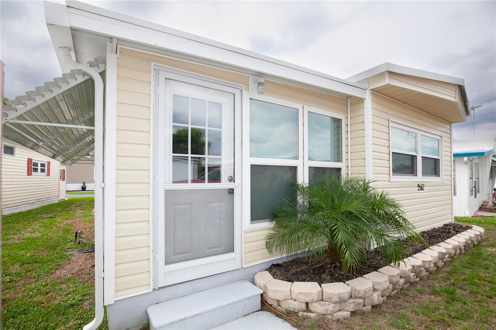 Welcome home! Situated right next to downtown Tavares on Lake Dora, this community sits at the mouth of the Dora Canal and offers many water amenities. This charming two bedroom home was completely renovated in 2022 and is being sold furnished. New siding, windows, metal roof was coated, new AC, flooring, kitchen, new appliances and bathroom. The cheery exterior brings you into the sunny Florida room with wall to wall windows and tile floors. Stepping inside the living room filled with natural light you’ll find neutral colors and wood style floors. The kitchen offers shaker cabinets, stainless steel appliances, beautiful backsplash with dining area. The primary bedroom features built in storage drawers, crown molding, and a half bath through a plantation shutter style door. The luxurious main bathroom showcases ample counter and cabinet space and a gorgeous shower with floor to ceiling tile. In the hallway you’ll find a spacious storage closet and a laundry nook with washer. The covered carport provides access to another storage room which could be utilized as a workshop with dryer. Walking distance to the community center, spend the weekends fishing out on the lake or play a game of shuffleboard with your friendly neighbors. Take a bike or golf cart ride to the downtown area and watch the planes take off from the seaport, have a drink with live music at one of th many downtown restaurants, visit community events and take a walk around Wooton Park. You also have quick access to shopping, medical facilities and major attractions, parks and airport. Come experience Florida living the way it was meant to be! Call today to schedule a showing to see this beautifully renovated two bedroom home in downtown Tavares.