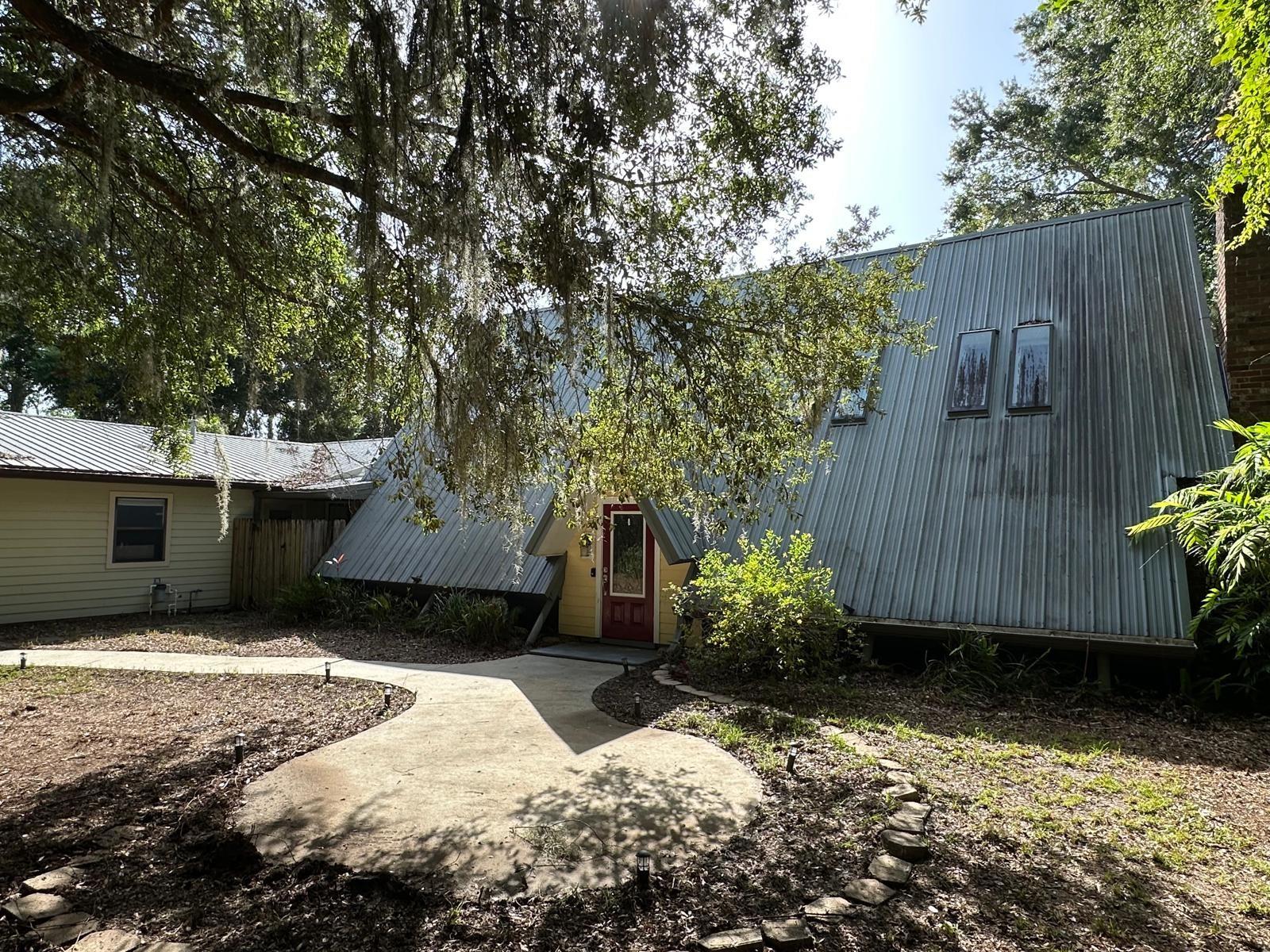 Multi-generational home with salt water filtrated pool, in-law suite and 3 car garage in DeLand. Here's you chnce to transform a spacious DeLand home into a standout property! Situated on a peaceful .65 acre lot with mature trees and elevation from the road, this home offers flexibility, privacy and room to grow. The 4/2 main home (2176 sq ft)has an open layout, high ceilings, and tons of natural light. It needs updtes and repairs but with a little TLC you can add some equity at this discounted price! The attached in-law suite offers a 1 bed/1 bath (912 sq ft) layout with full kitchen, laundry, private entry and pool access - perfect for Airbnb or guests. Enjoy the screened in pool, plus a 3-car detached garage with workshop and added storage shed. Metal roofs, fenced yard, and a lovely setting make this a solid project for your forever home, for flippers, or landlords. Minutes to Stetson University and DeLand High School.