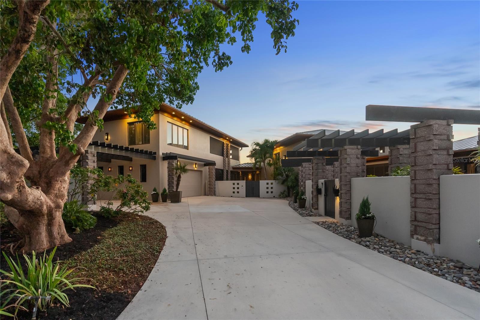 Designed by esteemed architect John Potvin, this exceptional home combines elegance with casual tropical charm. Created with flexibility in mind, its three distinct structures—connected by covered lanais—provide privacy and grand spaces for socializing. Stone columns, metal pergolas, and lush foliage enhance the serene atmosphere, while a stucco perimeter wall ensures ultimate privacy, complemented by the soothing sounds of a tranquil fountain.