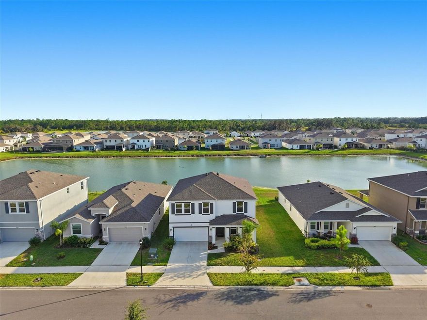 Barely lived-in and completed in 2024, this Avalon Park Wesley Chapel home pairs a bright, open layout with a waterfront setting full of life and movement. The lot is wider than most, offering breathing room between neighbors while framing tranquil views of the pond—where ducks, eagles, and sandhill cranes drift through at sunrise and dusk.
Inside, sunlight pours through the living, dining, and kitchen areas, creating a calm, cohesive atmosphere. The kitchen anchors the space with white shaker cabinetry, custom hardware, exotic granite counters, and a neutral earth-toned tile floor laid in a staggered pattern. A full pantry and dedicated coffee bar make the layout both stylish and functional. A smart Samsung fridge, a whole-home water softener and filtration system, and a matching washer and dryer add everyday ease.
The first floor includes a full bedroom and bath—ideal for guests or multi-generational living—along with a flexible den that works beautifully as an office or playroom. Upstairs, the primary suite captures sweeping water views that glow under the moonlight, while the large family room provides a natural gathering space for movies or downtime.
Life in Avalon Park Wesley Chapel centers around connection and community. Built around a “Live, Learn, Work, Play” concept, Downtown Avalon Park is actively expanding—already home to restaurants, ice cream shops, and year-round events, with more retail and office space underway. Each July 4th, fireworks light up the sky over the lake; on weekends, neighbors meet for food trucks at the clubhouse or volleyball near the park. Families enjoy access to excellent nearby schools, including New River Elementary and Wesley Chapel High—plus new charter and high schools under construction.
Nestled just off SR-54 with quick access to I-75, this home is minutes from The Shops at Wiregrass, Tampa Premium Outlets, The Grove, and The Krate. It’s the perfect mix of peaceful and connected—where natural light, thoughtful design, and everyday convenience all come together in one beautiful place to call home.