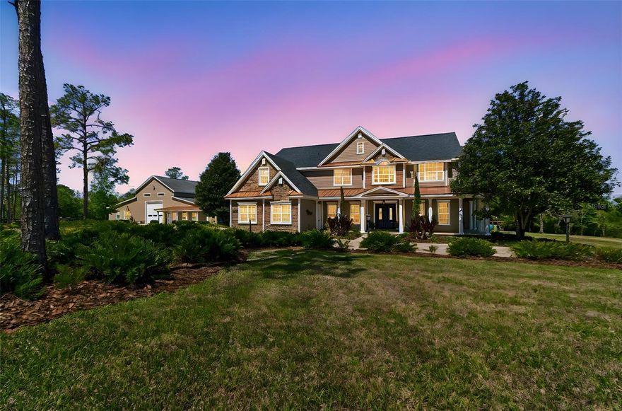 Tucked away at the end of a private paved road, this extraordinary estate offers luxury living surrounded by 21.7 acres of peaceful Florida countryside. Built in 2007 and meticulously maintained, the residence features 4 bedrooms, 4 bathrooms, a 3-car garage, and a resort-style pool, with a thoughtfully designed floor plan that blends comfort with elegant entertaining. The chef’s kitchen is equipped with high-end Viking and Miele appliances, including a gas cooktop, built-in coffee maker, and wine refrigerator, creating a space that is both functional and beautifully designed. The home also features a custom iron handrail along the staircase, adding to the craftsmanship and character of the interior.  Significant recent updates include a roof and all HVAC systems replaced within the past four years, providing peace of mind for the next owner.  The home is also equipped with a whole house generator.
Beyond the main residence, the property features an impressive 8,000 sq ft carriage house built to accommodate multiple motor coaches with drive-through capability, while also serving as an ideal space for a car collection, show cars, motorcycles, or large-scale entertaining. The building includes electric, water, multiple A/C units, a full bathroom, and its own septic system, along with a beautifully finished sitting room that could easily be converted into a private guest suite or mother-in-law quarters. A stunning custom bar and entertaining area make this an incredible space for gatherings, events, or multi-generational living.  A side-by-side utility vehicle and zero-turn mower are included and will convey with the property, offering added convenience for maintaining and enjoying the grounds.
The estate is further enhanced by a fully owned grid-tied solar system (no lease) that powers both the main home and carriage house, with current electric costs averaging approximately $40 per month, offering both efficiency and long-term savings.
This exceptional property offers a rare combination of luxury, privacy, and versatility, all within a convenient drive to major roadways, shopping, and dining. Properties of this caliber, offering substantial acreage, privacy, and extensive additional improvements, are rarely available. The property is ideal for RV or motor coach owners, car collectors, hobbyists, or those seeking a private family compound.