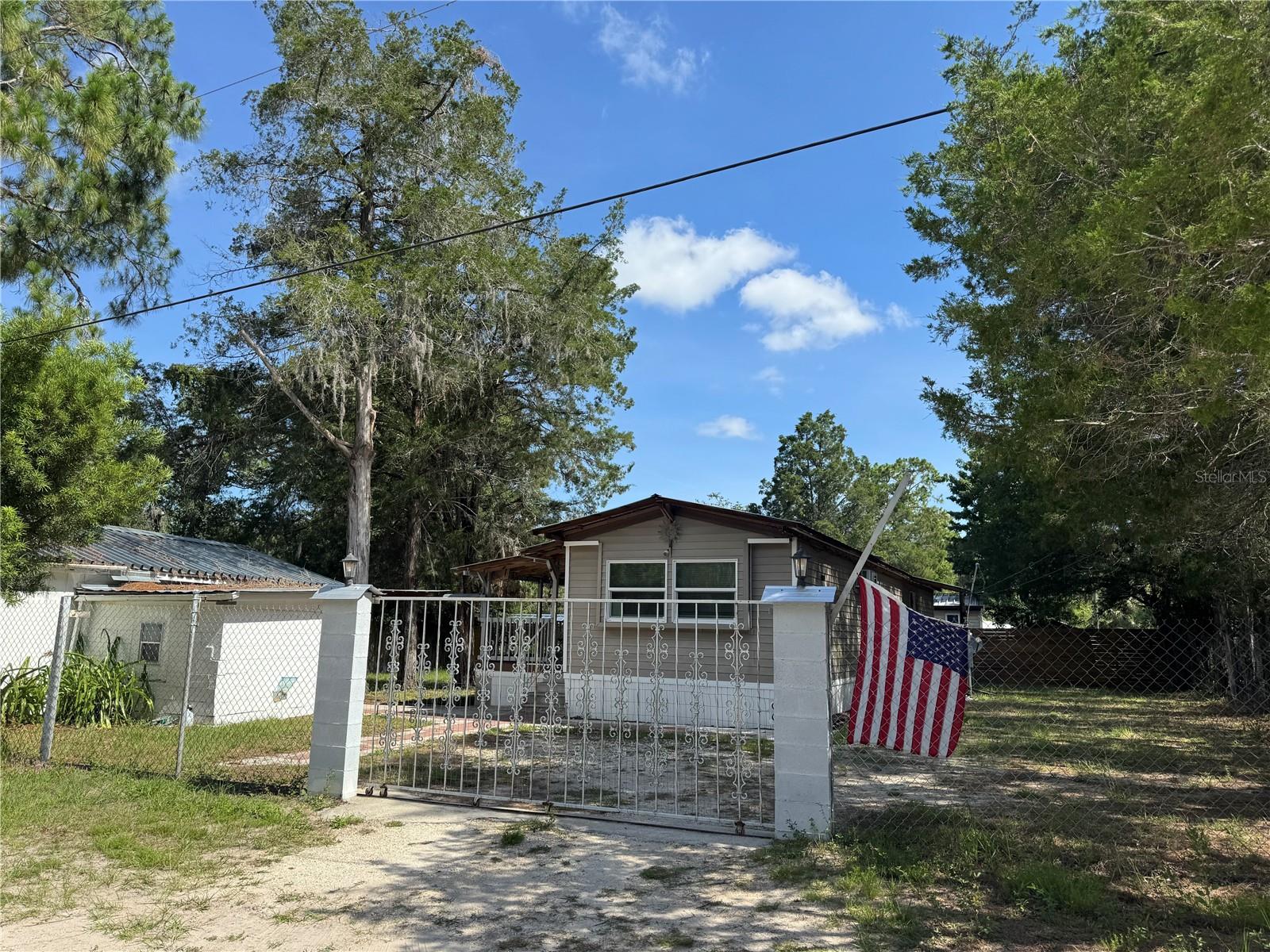 Beautifully renovated and fully furnished 2-bedroom, 1-bath single-wide mobile home on 0.23 acres, located just east of Hwy 19—only 5 minutes to Walmart and 10 minutes to a public boat ramp. Completely overhauled in 2021, this home features new double-pane Low-E windows, an insulated metal roof-over, pressure-treated framing with insulation, and new vinyl siding installed over the original aluminum. Interior updates include real hardwood floors, solid hardwood interior doors, wider exterior doors, and fully insulated walls for energy efficiency, noise reduction, and added structural strength. The updated underbelly, in-wall A/C units in every room, and a spacious new kitchen (2022) with granite breakfast bar provide both comfort and modern style. The tiled bathroom includes a waterfall tub/shower combo and a new water heater installed in 2023. Enjoy a large covered front porch (11’x16’) with composite decking, a private fenced backyard with fruit trees, and an oversized 18’x26’ one-car garage with a metal roof, laundry room, and workshop area. Additional features include updated septic system (2011), a new well pump and tank (2023) and a 2024 Water Softener. High and dry lot with wrought iron gates—no HOA, no lot rent, and move-in ready!