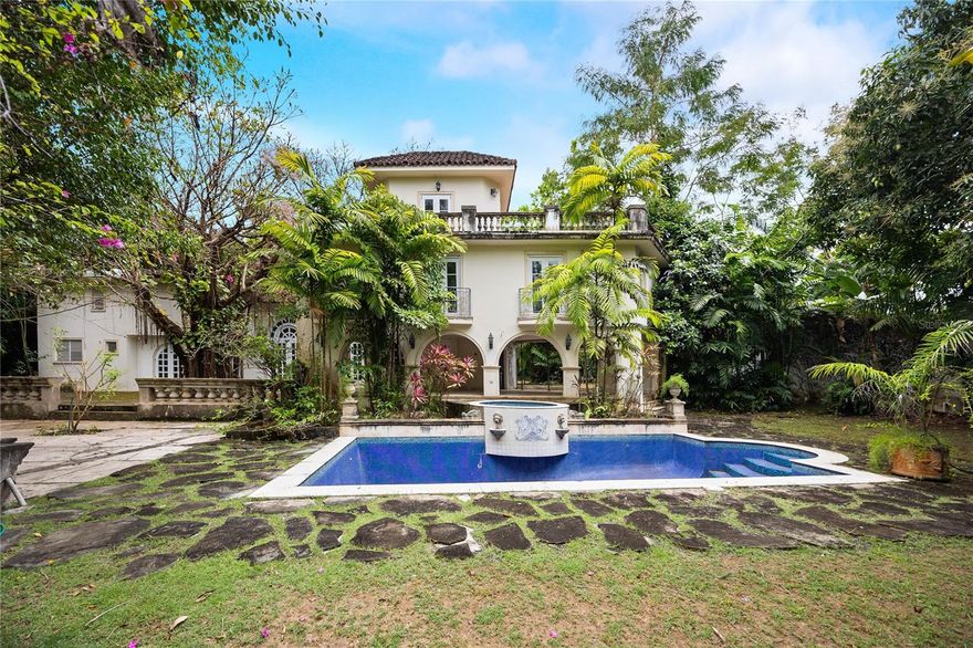Majestic Mediterranean Estate in Urb. San Patricio! Discover a timeless architectural gem nestled on 1.5 cuerdas of lush, tree-lined terrain in the exclusive Urb. San Patricio. This Mediterranean-style masterpiece offers an unparalleled blend of elegance, comfort, and natural beauty.
The two-level residence features soaring ceilings in the main living area, accentuated by a striking staircase—an architectural centerpiece that gracefully leads to the upper level. The home is designed with open, flowing spaces perfect for both formal entertaining and relaxed living, including expansive areas for the living and dining rooms.
Outdoors, an expansive open plaza surrounds a captivating Ficus tree, creating a natural gathering point with serene views of the verdant backyard. A covered terrace seamlessly connects to the inviting pool area, ideal for enjoying the Caribbean climate year-round.
Additional features include a detached two-car garage, a utility room, and backup power equipment to ensure convenience and peace of mind. This property also presents an exceptional opportunity for personalization. With remodeling envisioned, it offers the flexibility to incorporate your own needs and desires—whether it’s modern upgrades, custom finishes, or tailored spaces that reflect your lifestyle. We have available architectural drawings and specs for a quick remodeling of the current state. Some photos have been virtually staged for illustration.
